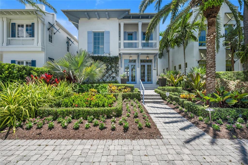 Located in the heart of Olde Naples and designed by Jeff Harrell and Associates, the architecture of this beautiful 2-story home reflects a West Indies style with crisp white stucco and iris blue accents. Built in 2014, the Molineaux floor plan features three bedrooms, three baths and a powder room. With its open floor plan, soaring ceilings, floor-to-ceiling windows and numerous French doors, there is a view of the lushly landscaped lanai and pool from the main living areas. The pool area features an outdoor gas grill, plenty of patio area for lounging and dining along with a spa and fire bowl waterfalls. There is also a custom awning designed to offer shade over a portion of the lanai, a helpful addition for a break from the warm Naples sunshine. The chef’s kitchen with marble counter tops, Viking gas cooktop/oven, wine cooler, and Miele appliances including convection microwave, steam oven, refrigerator/freezer and dishwasher. The center island is the perfect place to gather for all types of dining/entertaining. The walk-in pantry with built-in shelving and sliding barn door is conveniently adjacent to the kitchen preparation areas. The kitchen, great room and dining area feel open and inviting, with natural light entering the space from both the front and back French doors. The first floor also features an indoor lanai/family room space, with built-in bar with marble top, wine cooler, wall of sliding glass doors and motorized screen. This space can be used with doors open and screen down during cooler weather or as additional air conditioned living space. Off this area is the first floor guest bedroom and full bath with access to the pool area.  The powder room is tucked around the corner, at the front of the house. The second floor features another guest bedroom with bath and balcony and laundry with sink. The primary suite. with his and her walk-in closets, offers soaring ceilings, floor-to-ceiling windows with view of pool area. The primary bathroom with separate soaking tub, shower and dual vanities features floor-to-ceiling corner windows. Additional features include Legno Bastone European wide plank floors, impact doors and windows, concrete block construction on both floors, standing seam metal roof with custom color, automated window coverings throughout, tankless hot water heater, whole house generator, AC units w/ separate zones, Elan g! home automation system with surveillance, sound and lighting. Two car garage is accessed from private alley. Important to note that this area of Naples has natural ‘in-ground’ gas to service generator, hot water heater, pool heater, outdoor grill, kitchen gas cooktop, fire bowls.