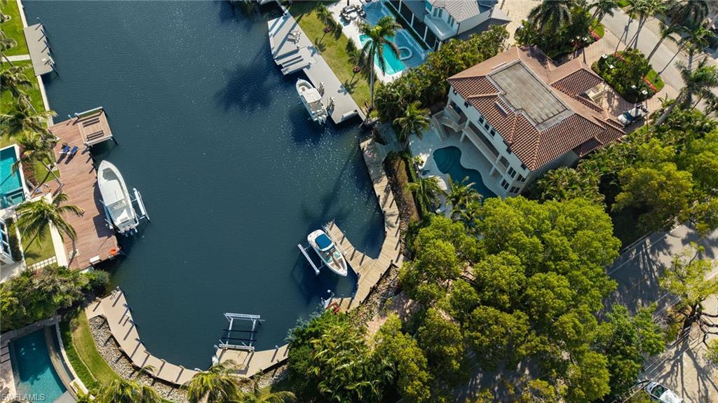 A rare opportunity to own one of the most coveted waterfront properties in Aqualane Shores—now at an incredible value. With over 135 feet of deep-water frontage along one of the neighborhood’s widest canals, this oversized corner lot offers the kind of dockage that serious boaters dream about. Direct Gulf access, multiple slips, a wraparound dock, and open water views—this is where luxury meets lifestyle.

Tucked away on 1825 6th Street S, this estate sits on approximately 0.37 acres at the end of a quiet canal, offering unparalleled privacy and panoramic water views. With immediate proximity to Naples Bay and no bridges, this is a premier location for those seeking effortless boating and refined coastal living.

The three-story home spans 4,487 square feet under air with 4 bedrooms, 3.5 bathrooms, a main-floor primary suite, and an office. Soaring ceilings in the living room create an impressive entrance, seamlessly connecting to the open-concept kitchen and dining areas. A custom elevator leads to the upper level with three guest suites and a loft-style sitting area.

The ground floor opens to an additional 1,400 square feet of air-conditioned space—ideal for entertaining, a gym, or game room. Step outside to the large and inviting pool and spa, outdoor kitchen, and expansive deck that makes the most of the stunning waterfront setting.

For the boating enthusiast, the dock includes two slips with lifts, a separate platform for kayaks or jet skis, and deep water that can accommodate larger vessels—an offering that sets this property apart from the rest.

Interior finishes include quartzite countertops, custom cabinetry, stone flooring, impact-resistant windows, and an updated primary bathroom—providing both style and function. Move in and enjoy, or reimagine the property into your dream estate on one of Aqualane’s premier lots.

Located just a short walk to the beach and Naples’ famed 3rd Street South dining and shopping district, this home offers the perfect blend of seclusion and access.

This is the best waterfront value in Aqualane Shores—don’t miss your chance to own a true boater’s paradise.