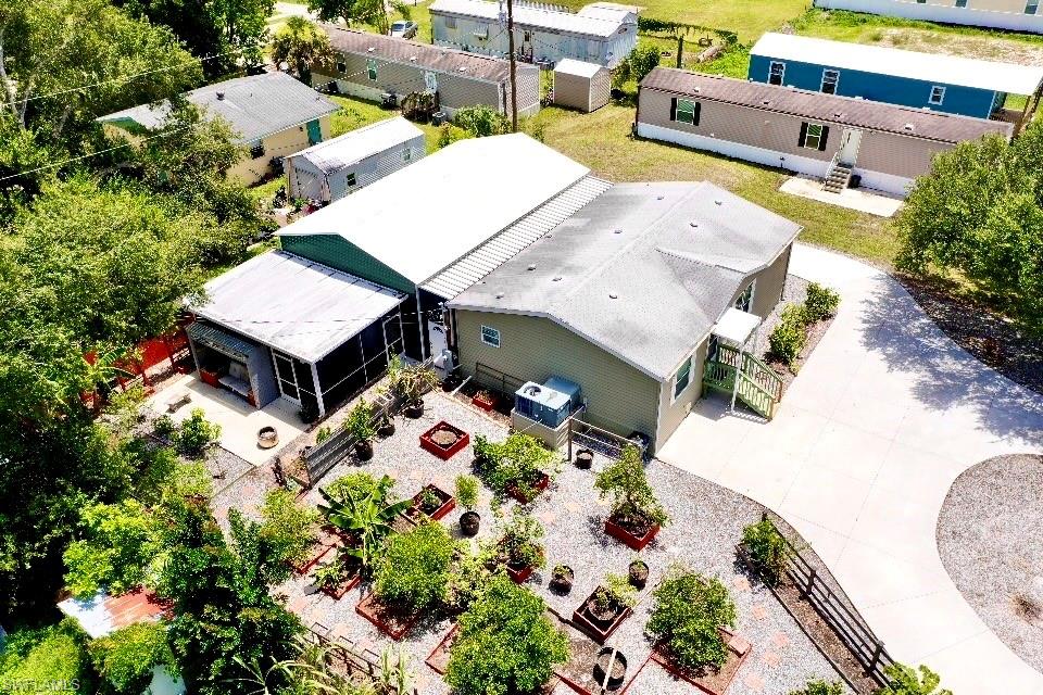 Welcome to 356 Sacramento Street, a 2019-built home offering 2 bedrooms, 2 baths, and just under 1,200 square feet on a quarter-acre lot in North Fort Myers — close to shopping and just a short drive from downtown Fort Myers. A mature oak shades the front yard, and the side of the home is lined with an established fruit tree garden set in raised planter beds with banana trees and gravel walkways. Step inside to an open layout where the living room, kitchen, and dining area all connect. The living room features two wood shiplap accent walls and a built-in electric LED fireplace, while crown molding, ceiling fans, and dark wood-look vinyl plank flooring carry through the entire home. The kitchen is the centerpiece, with generous white custom cabinetry, a gray island finished in Black Galaxy granite, stainless steel appliances, a tile backsplash, and pendant lighting. Both bedrooms are well-sized, and each comes with its own private attached bath finished with matching granite and custom cabinets — an ideal setup for guests, family, or roommates. Double-pane windows throughout keep things comfortable year-round. Out back, the standout is a 28x40 steel building connected to the home by a covered walkway, complete with two 10x10 roll-up doors, 12-foot peak ceilings, and a wide concrete apron for parking — already outfitted as a workshop with plenty of room left over for vehicles, projects, or storage. Just beyond it sits a 14.5x21 screened-in lounge with green shiplap walls and a second built-in LED fireplace, a comfortable spot to unwind in the evenings. Home is prewired and set up for a generator hookup.  Well-kept, versatile, and ready to go! Perfect for a home business set up or those wanting an ultimate home garage!