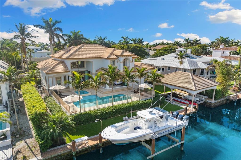 Just around the corner from Third Street South, this waterfront home offers a blend of convenience and luxury, with dining and shopping mere steps away. A boater’s paradise, it features a deep-water 24,000-pound lift, a 22-by-29-foot covered boathouse with an additional 16,000-pound dual lift, and direct Gulf access. Go inside to discover a serene retreat, where a two-story family room flows effortlessly to an expansive pool deck, bordered by low-maintenance synthetic turf. The primary suite includes a luxurious main bath with dual vanities, a soaking tub, shower and two walk-in closets with custom built-ins. The gourmet kitchen boasts granite countertops, high-end appliances and exquisite custom woodwork. Upstairs, find three additional bedrooms and a second-story loft, ideal for versatile living. Additional features include a three-car garage, a Lutron lighting system, including automated shades and thermostat controls. Seawall cap, seawall tie backs, new dock and lift all added in 2020. The exterior was painted in 2025 and the interior was painted in 2023. Experience the best of Naples waterfront living, just moments from dining, shopping and the beach.