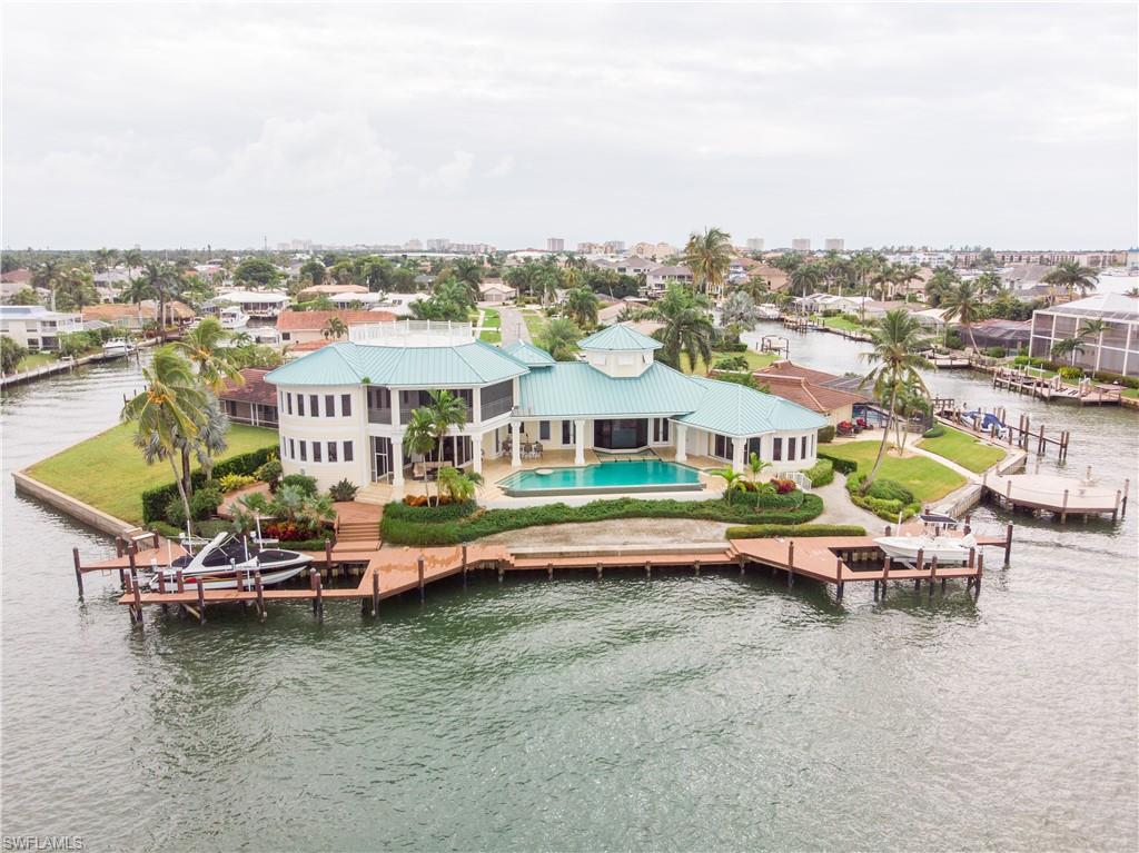 THIS IS ONE OF THE MOST IMPRESSIVE PROPERTIES ON THE MARCO RIVER! This is a true TIP property with 193'ft of direct access water frontage that features unobstructed views of the River..it is a boaters delight! Upon entering this custom designed home you are met with a two story glass enclosed foyer that views the infinity edge pool and spa than tumbles visually into the river. ON the lower level, 10'ft sliders around, open to an extensive wrap around lanai and outdoor entertaining area. Custom Jerusalem stone and bamboo hard wood flooring throughout ideal for Florida living. Gourmet kitchen features granite counters and custom cabinets,work desk,large pantry and upscale stainless appliances.Adjoining utility room. Glass enclosed breakfast nook, plus separate dining room. Den features extensive built-ins. Spacious ground floor master bdrm, features twin walk-in closets adjoining master bath with soaking tub and large walk-in shower. Upper level, features 2 bedrooms and a large Bonus area for gathering..with extended balcony and access to upper level observation platform . Extensive boat dockage with 2 lifts. Three car garage ,paved driveway.Furnished per inventory.AMAZING!