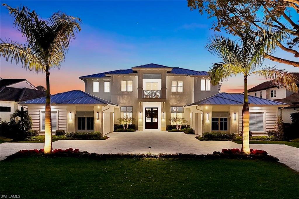 A true Gem in the heart of the Moorings. Timeless, elegant design, superior craftsmanship, and a light-filled southern exposure come together seamlessly in this stunning 5 bedroom plus den, new construction home – offering 6,130sqf. of exclusive living space at an exceptionally attractive price per square foot.
The residence is located on a desirable and expansive FEMA  X500 lot on Riviera Drive with its gorgeous tree-lined canopy and was built by Dillman Construction, one of Naples’ premier luxury builders. It features an expansive two-story floor plan that offers exceptional living and entertaining opportunities on both downstairs and upstairs living areas along with beautiful outdoor patios and terraces on each level. The spacious primary suite is a relaxing haven, complete with a spa-inspired bathroom, while 2 further bedroom suites on the main level and two additional suites upstairs provide generous accommodations for family and guests.

The interior reflects refined luxury throughout, highlighted by extensive custom woodwork and wainscoting and Legno Bastone oak flooring that enhance the home’s elegance. The chef’s kitchen is outfitted with Sub-Zero and Wolf appliances and includes a concealed walk-in pantry with custom cabinetry perfect as a coffee/beverage bar. Other features include an elevator, whole-house generator, two linear fireplaces, a Lutron lighting system, and spacious garages with air-conditioned storage.  Outdoors, the spectacular south facing grounds showcase a 40-foot lap pool with waterfall and spa, multiple fire features, and an expansive outdoor living area with linear fireplace and kitchen.  An outdoor shower, and electric screens and shutters complete the experience. All of this is complemented by beautifully landscaped, private grounds that offer tranquil views from every room. Private beach access with parking is available through the Moorings Property Owners Association for a nominal fee.