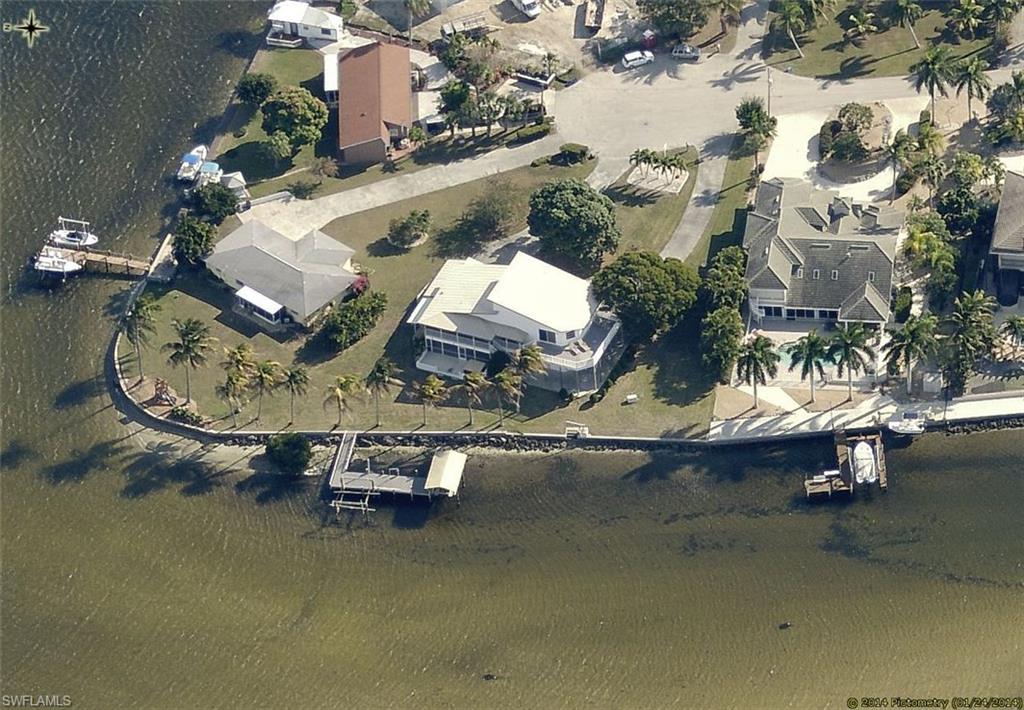 NOW THIS IS WATERFRONT LIVING AS IT SHOULD BE!! Approx Three Quarter acre lot with 225' of sea walled bay frontage and two 10,000# boat lifts, one will accommodate a 14' wide boat. Gigantic circle driveway!  Quick, direct access to some of the best sports fishing waters in the world. Central water and sewer.  2 car garage plus 25x30 garage, w/16' ceiling for RV or motor home and carport for motor home. Composite decking!  4 bedrooms, 3 baths and spectacular sunsets!     Screened entry leads to an elegant entry door that opens to a breathtakingly panoramic view of Matlacha Pass through a triple sliding door that graces the tiled entertaining area with it's wet bar and upscale cabinetry.  A 2 story wall of white Georgia marble greets you in the ante room and an open staircase leading to the second level. The 2nd level, the main living area, has a large living room, kitchen, formal dining room, a bedroom (or office/den) and bath.  The master suite, a few step up, on the 3rd level, encompasses a 24x29 area.  Composite decking surrounds the master suite and has dazzling sunset views. Split a/c system,  and a huge circular driveway complete this amazing package!