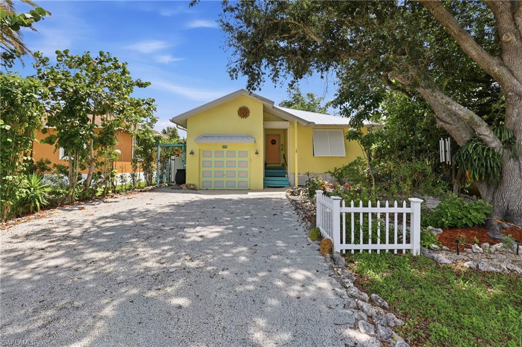 One or more photo(s) has been virtually staged, AI generated or rendered.  BOTANICAL PARADISE MEETS KEY WEST CHARM IN THE HEART OF NAPLES

Tucked away in the welcoming community of Trail Acres, this truly one-of-a-kind Key West-inspired residence offers a rare combination of tropical beauty, exceptional efficiency, and easy Florida living. Situated on a beautifully landscaped homesite, the backyard is nothing short of a botanist's dream, showcasing more than 100 species of plants, mature fruit-bearing trees, vibrant rock gardens, aloe plantings, and thoughtfully designed outdoor living spaces that create your own private tropical retreat.

Designed to embrace the Florida lifestyle, the outdoor amenities are exceptional. Enjoy a covered front porch, screened lanai for year-round dining and relaxation, and a charming 10' x 10' screened Chickee Hut with thatched roof handcrafted by local Seminole artisans. The fenced backyard also features solar-powered landscape lighting, ten rainwater collection barrel systems, a storage shed, chicken coop, and numerous garden areas perfect for gardening enthusiasts or anyone seeking a peaceful outdoor sanctuary.

Built for both comfort and peace of mind, this home is equipped with Bahama hurricane shutters, remote-controlled roll-down metal storm shutters, a low-maintenance white metal roof, and a 2021 Trane HVAC system. The home's remarkable energy efficiency results in electric and water bills averaging under $60 per month.

Inside, all living areas are conveniently located on one level. The entry foyer opens to a comfortable living room with abundant natural light and hurricane-protected windows. The bright kitchen offers white cabinetry, white appliances, a sunny breakfast area, and sliding glass doors leading directly to the screened lanai—perfect for seamless indoor-outdoor entertaining.

The primary suite features a walk-in closet and private en-suite bath. Two additional bedrooms each include walk-in closets with custom built-ins and hurricane shutters, providing flexibility for family, guests, or a home office.

Additional highlights include a one-car front-loading garage complete with storage loft and laundry loft, a paver and gravel driveway accommodating up to four vehicles, public water and sewer, central air conditioning, forced-air heating, and numerous thoughtful upgrades that make this home both economical and exceptionally easy to maintain.

Whether you're searching for a full-time residence, seasonal retreat, or unique Florida getaway, this distinctive home offers an unmatched blend of tropical charm, sustainable living, and outdoor enjoyment that's rarely found in Naples.