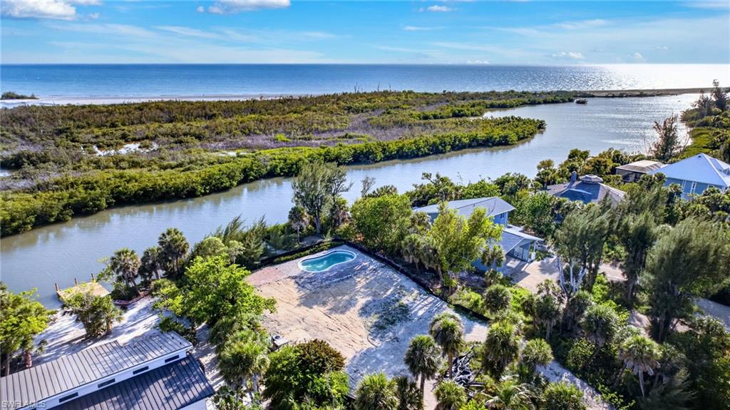 Discover an extraordinary opportunity to create a legacy property in one of Sanibel Island’s captivating natural settings. Along the tranquil banks of Clam Bayou and encompassing nearly one acre of land, this exceptional homesite offers the ideal foundation for a custom waterfront residence designed to embrace the beauty, serenity and timeless allure of island living. Already enhanced with a cleared building site, an existing in-ground pool and a newly constructed private dock, the property is uniquely positioned to accelerate the journey from vision to reality. Here, every day begins with panoramic views across the protected waters of Clam Bayou, where mangrove islands rise from the landscape and an abundance of native wildlife creates an ever-changing natural spectacle. Beyond, glimpses of the Gulf waters complete a breathtaking backdrop that promises unforgettable sunsets and a profound connection to Sanibel’s celebrated coastal environment. Located within the ecological zone Upland Wetland (D2), the property offers approximately 25% allowable impervious coverage and 30% allowable developed-area coverage. Based upon the Lee County Property Appraiser’s reported lot size of 37,407 square feet, this equates to approximately 9,350 square feet of impervious area and approximately 11,222 square feet of developed area, providing remarkable flexibility for the design of a substantial custom residence and outdoor living environment. Whether your vision includes expansive terraces overlooking the bayou, walls of glass framing the surrounding natural beauty, a resort-inspired poolside retreat, guest accommodations or dedicated spaces for entertaining, this generous homesite presents a rare opportunity to design without compromise. New construction also offers the confidence and peace of mind that comes with modern engineering standards and the latest building codes, allowing you to create a home that is both beautiful and resilient. From your private dock, launch a paddleboard, kayak or small boat and explore the winding waterways that make Sanibel one of Florida’s most treasured island destinations. Spend your mornings gliding through quiet mangrove tunnels, your afternoons observing dolphins, manatees and shorebirds and your evenings enjoying the spectacular colors of the Gulf sky reflected across the bayou’s calm waters. Opportunities of this caliber are increasingly rare: a nearly one-acre waterfront homesite, thoughtfully prepared for development and surrounded by protected natural beauty. Here, the setting is inspiring, the possibilities are extraordinary and the lifestyle is unmistakably Sanibel.