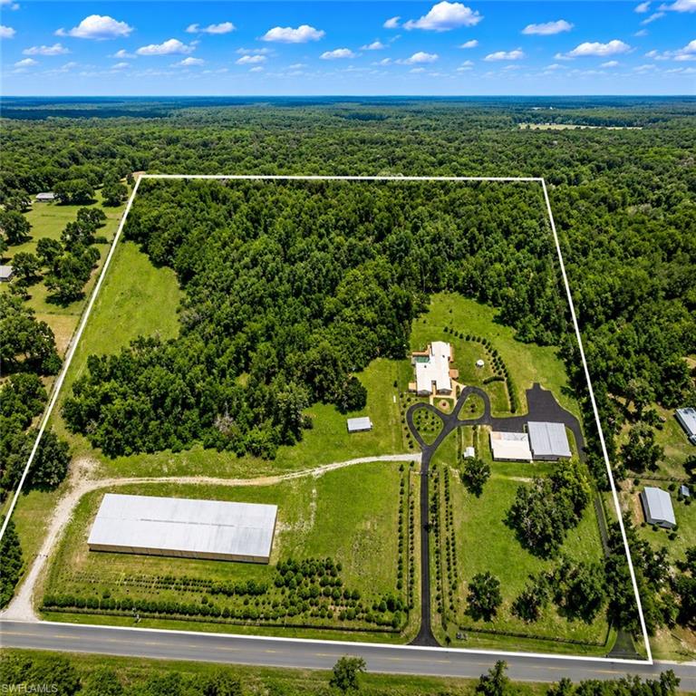 A rare opportunity to own a truly exceptional 24-acre Brooksville estate offering an unmatched combination of luxury residential living, equestrian potential, industrial capability, and future development flexibility. Designed for both grand-scale entertaining and everyday comfort, the custom 6,700 sq ft main residence features 5 bedrooms, including 3 suite-style bedrooms, 5.5 bathrooms, large executive office, and expansive living spaces including a living, sitting and great room complete with a full bar. The home is enhanced by 3 fireplaces and an impressive 2,500 sq ft two-story wraparound deck spanning three sides of the residence, along with a pool deck and hot tub designed for outdoor relaxation and entertaining. The home captures panoramic natural surroundings, privacy, and exceptional airflow. For the automotive enthusiast or serious collector, the estate offers extraordinary, fully scalable vehicle capacity exceeding 100 cars in total across multiple structures. The eight-car garage with integrated paint booth provides space for approx. 9 vehicles while also including dedicated storage and a professional-grade paint stall. The 4,800 sq ft high-bay building with 20-foot ceilings and oversized doors can accommodate approximately 18–22 vehicles, RVs, or heavy equipment. The crown jewel is the 24,500 sq ft commercial-grade building, which can house approximately 65–80 vehicles, offering exceptional clear-span interior space ideal for collectors, storage operations, or automotive business use. Additional structures include a 4,800 sq ft high-bay building and a 24,500 sq ft wind-rated commercial-grade facility constructed approximately 12 years ago, featuring 16-foot eaves, a 140 MPH wind rating, and flexible interior layout suitable for industrial, logistics, storage, or event use—making it one of the largest privately owned structures of its kind in the region. Equestrian amenities include a small horse stable and ample acreage suitable for paddocks, riding areas, or expansion. Extensive environmental due diligence has been completed, including a Wetlands Jurisdictional Delineation, Protected Wildlife Species Survey, and full property survey, significantly reducing development risk and streamlining future permitting or subdivision opportunities. The property also features a highly flexible subdivision plan allowing for up to five total parcels, including a primary estate parcel with the main residence and supporting structures, a dedicated commercial/industrial parcel featuring the 24,500 sq ft building, and three additional residential lots ideal for custom homes, guest estates, or resale potential. Offering nearly 36,000 sq ft of enclosed structures across the estate and unmatched vehicle storage capacity exceeding 100 cars, this property is ideally suited for private estate ownership, multi-generational compound living, agricultural or equestrian operations, or a high-value investment and redevelopment strategy. A truly one-of-a-kind!