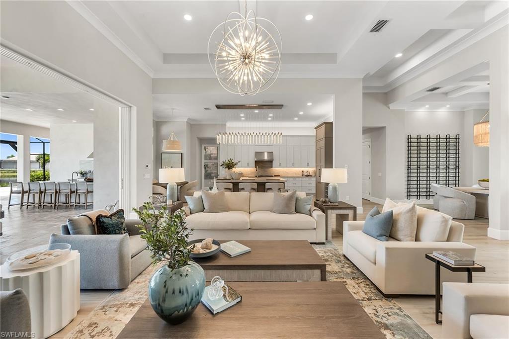 Once-in-a-lifetime opportunity to own a piece of paradise in one of the sought-after coastal communities in the world. Ideally just moments from the world-renowned boutiques, restaurants, and coastal energy of downtown Fifth Avenue, and equally close to the sugar-white beaches of the Gulf, this newly completed custom residence by Stock Construction is a home designed not simply to be admired but to be experienced. From the moment you arrive through the private gated entry, a sense of quiet sophistication unfolds. Inside, nearly 3,600 square feet of impeccably curated living space is defined by soaring custom coffered ceilings, exceptional craftsmanship, and an effortless connection between indoor elegance and the breathtaking natural beauty beyond. Walls of hurricane-impact glass frame uninterrupted lake views, transforming every room into a living portrait where shimmering water and vibrant sunsets become part of everyday life. Designed for intimate moments and unforgettable gatherings, the residence offers four spacious bedroom suites, a versatile den or executive office, and five beautifully appointed baths. At its heart, the chef's kitchen is a masterclass in beauty and function, featuring natural gas cooking, bespoke cabinetry and exquisite finishes that inspire everything from quiet morning coffee to elegant dinner parties. Life here extends far beyond your front door. Within The Isles of Collier Preserve, a community inspired by the timeless architecture and enduring character of Old Naples, residents enjoy an exceptional lifestyle immersed in nature. More than half of its 2,400 acres have been preserved as pristine lakes, wildlife habitat and protected natural landscapes. Miles of scenic recreational, biking and kayaking trails wind through the Cypress Waterway, creating an everyday connection to Southwest Florida's remarkable beauty. At the center of the community, The Isles Club offers an amenity experience that rivals a private resort, featuring a state-of-the-art fitness center, resort and lap pools, tennis and pickleball courts, the Overlook Bar & Grill, multiple kayak launches, and miles of waterways perfect for paddleboarding, kayaking or simply embracing the peaceful rhythm of life on the water. This is more than a newly constructed luxury residence, it is an invitation to embrace one of Naples most desired lifestyles.