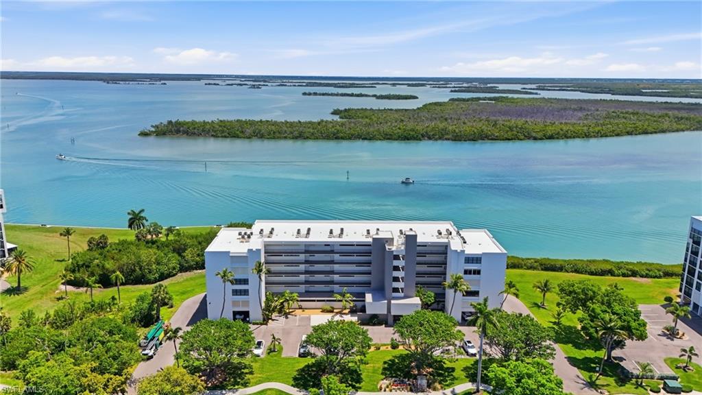Experience breathtaking Estero Bay views from this beautiful 2-bedroom, 2-bath residence in the desirable Palms community. Designed to capture the beauty of its waterfront setting, this light-filled condo features impact-resistant sliding glass doors and windows, allowing you to enjoy the scenery with peace of mind. The inviting living and dining areas are furnished in a stylish contemporary design, creating a comfortable coastal retreat. The kitchen offers ample cabinetry, stainless steel appliances, recessed lighting, and a convenient built-in desk area. Both bathrooms have been tastefully renovated with modern finishes, while the spacious owner's suite showcases panoramic bay views through an entire wall of windows, providing a stunning backdrop to wake up to each day. The guest bedroom is bright and airy, featuring high-set windows that welcome abundant natural light from the desirable southern exposure. Additional conveniences include an in-unit washer and dryer, under-building parking, and extra storage. Residents enjoy an impressive array of amenities, including deeded beach access, a large community pool, exercise room, fishing pier, tennis and pickleball courts, bocce ball, walking paths, and a community room. Located on the quiet south end of Fort Myers Beach, The Palms offers a relaxed coastal lifestyle just moments from the white sand beach, public marina, and nearby Bay Beach boat docks. Seller has boat dock with  brand new lift and decking available for purchase. This is waterfront Florida living at its finest where spectacular views, resort-style amenities, and a prime location come together.