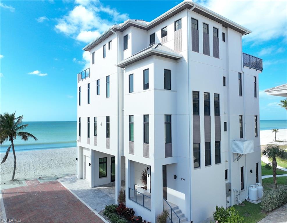 This 4 story Barefoot Beach Front Home offers Gulf views and sunsets that will take your breath away from every floor and every room.  The timeless coastal contemporary design, detailed care and maintenance of this home makes it feel as if it was just completed.  The 5,782 AC SQ FT provides for a spacious open floor plan, Grand living areas, generous room sizes, 5 bedrooms + den, 7-baths including a second cloud living area.  The 9,472 total living SQ FT provides for amazing outdoor living areas, summer kitchen, open decks, pergola deck with gas fire bowl all right on the beach plus a car collector size garage.  The value of this beachfront site cannot be understated as there will never be a home built close to this home on the beachfront where it is 218 feet to the next beachfront home to its north and 30 feet to the south, whereas the normal side setbacks between homes in Collier County and Naples are just 7.5 feet. Add to that there are no public beach access points within the Barefoot Beach community you have one of the most private beach settings imaginable. Windover Development, Kukk Architecture, Potter Homes and Freesyle Interiors, all first class, brought their best to create this amazing home.  Offered turnkey furnished so you can move right in and enjoy this season. The main level chef’s kitchen includes Wolf/Sub-Zero appliances, quartzite countertops, custom wood cabinets & classic white oak hardwood floors and opens to the dining room, great room & outside lanai via 10’ electric sliding glass doors plus guest bedroom 2 w/ensuite bath & a half bath. The master bedroom, bath and private lanai are spread across the whole width of the home where you feel like you are floating on the Gulf from your bed or the freestanding tub. The office/den has private access from the master bedroom and bedroom 3 w/ensuite bath & laundry complete the 3rd level. The top floor offers a large cloud living room with detailed vaulted ceilings and guest bedrooms 4 & 5 both w/ensuite baths plus an open deck with fire bowl.  Amenities inc Crestron home automation, private elevator, detailed millwork including ceilings, designer plumbing & light fixtures,  concrete construction, Andersen impact windows, motorized screens, storm shutters & sliders, plus aluminum snap-clad metal roof system. Barefoot Beach, Collier County’s premier gated beach to bay community, amenities include 24 hour guards and patrols, Clubhouse with fitness, tennis, pickleball full time on site Manager, beach garden pool and more. Option to join the Club at Barefoot Beach WITH NO WAIT (located in the community) which offers casual & fine dining restaurants, pool & beachside food, drinks, chair service, indoor & outdoor bars, ice cream & coffee shop, tennis courts with pro & a full events calendar. Minutes to Mercato, Coconut Point Mall, Promenade & Waterside, the airports and golfing.  Boat docks are available for lease or purchase right across the street.
