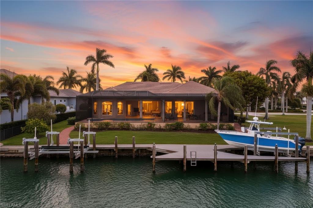 Set along the coveted southern stretch of Caxambas Court, this exceptional waterfront estate delivers the ultimate Marco Island boating lifestyle with prized southern exposure and swift, deep-water access to the Gulf—less than 900 feet away via Caxambas Pass. Custom built and thoughtfully designed, the residence spans three bedrooms plus a private office/den and four full baths, all complemented by a three-car garage and an impressive half-acre estate lot with 125 feet of direct water frontage.

Inside, refined craftsmanship and upscale finishes define every space. A generous split-bedroom layout is enhanced by soaring ceilings, solid-core doors, elegant crown molding, plantation shutters, and carefully curated lighting throughout. Impact-rated windows and newly installed remote-controlled storm shutters provide peace of mind, while the home’s elevated construction adds both security and presence.

At the heart of the home, the gourmet kitchen is tailored for both everyday living and entertaining, featuring custom cabinetry, granite counters, stainless steel appliances, dual ovens, an ice maker, a spacious walk-in pantry, and a striking backsplash illuminated by under-cabinet lighting. A nearby wet bar seamlessly connects the kitchen, casual dining area, and formal dining room—ideal for hosting guests.

The primary suite is a serene retreat with a sitting area, dual walk-in closets, and a spa-inspired bath offering double vanities, a walk-in shower, jetted soaking tub, and additional storage. Two guest suites provide private ensuite baths, while a fourth full bath serves the office/den and functions perfectly as a pool bath.

Outdoor living takes center stage through zero-corner sliders opening to a newly screened panoramic lanai. The expansive covered area features brick pavers, a brand-new summer kitchen with built-in grill, and ample space for dining and entertaining. The custom pool and spa, outfitted with new equipment and an Aqualink system, invite all-day enjoyment in the sun.

Boaters will appreciate the substantial dock with two lifts, including a 30,000-pound lift capable of accommodating a large vessel or yacht, all within a protected harbor setting. From your lanai, enjoy daily encounters with dolphins and manatees, world-class fishing, and effortless access to open water. Rarely does a property combine this level of craftsmanship, lot size, and premier southern Marco Island location—an extraordinary opportunity to own on Caxambas Court.

Ideally located just minutes from Marco Island’s pristine beaches, renowned dining, boutique shopping, and everyday conveniences, this exceptional property offers the best of island living. An outstanding opportunity to embrace a refined coastal lifestyle where elegance, comfort, and location come together seamlessly.