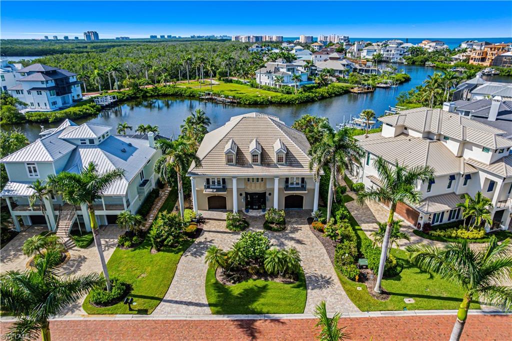Beautiful Gulf-access estate with breathtaking bay views in the exclusive, double-gated Southport on the Bay, located within North Naples’ highly sought-after Barefoot Beach community. With coveted Southern exposure, you’ll enjoy spectacular sunsets and prime sun over the pool. A true paradise for boaters and beach lovers, this property offers direct Gulf-access (no bridges) in minutes from your private dock with dual lifts and is just a short 5-minute walk to the pristine sands of Barefoot Beach. Offering 4,927 sq ft of living space, this coastal retreat features 4 bedrooms + den, 3.5 baths, tile and wood flooring, hurricane-impact windows, storm shutters, new HVACs (2023 & 2020), BRAND-NEW FLOOD BARRIER SYSTEM, and a NEW 2025 TILE ROOF. The open-concept chef’s kitchen showcases white cabinetry, granite countertops, high-end appliances including a gas & electric range, an oversized island with breakfast bar seating, and flows seamlessly into a bright sitting/dining area with expansive windows that fill the space with natural light. Step outside to a spacious balcony with panoramic bay views overlooking the large pool—an ideal setting for outdoor living and entertaining. The primary suite features elegant French doors to the upper balcony and a generous en-suite bath with dual vanities, a soaking tub, and frameless glass shower. Additional highlights include a ground-floor flex space, private elevator, 4-car garage (with a lift), wet bar with built-in beverage cooler, wine storage room, and a cozy gas fireplace. Optional membership to the exclusive "Club at Barefoot" provides access to tennis, two restaurants, beachside food and beverage service, and more. Conveniently located near fine dining, RSW Airport, Mercato, and Waterside Shops, and just 15 miles from the renowned Fifth Avenue in Naples, this home is a true gem in the heart of Barefoot Beach.