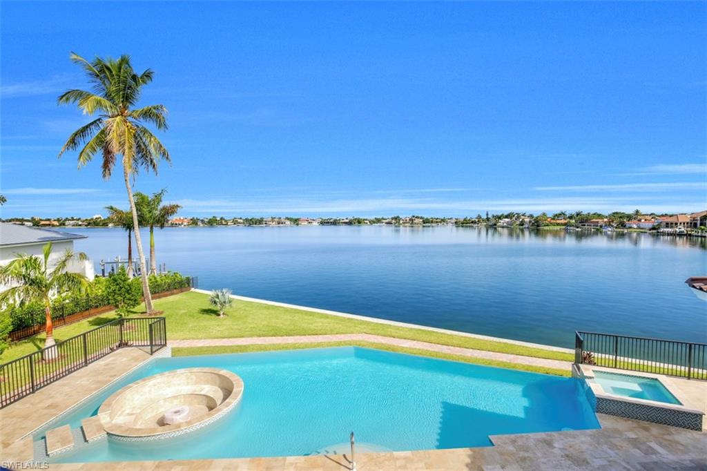 This brand-new contemporary coastal custom residence captures stunning water views of Roberts Bay in the prestigious Estates of Marco Island. Situated on half an acre of property with 168 feet of direct access and serene bay frontage, this commanding estate features four spacious bedrooms, five-and-two-half baths, den/office, game room/theater, formal dining room, expansive family room overlooking sparkling bay views, butler’s pantry, gourmet kitchen with breakfast seating, wine cellar and wet bar. Additional features include private elevator, four-car garage, two summer kitchens, large covered lanai space with electric screens and shutters. Enjoy the spectacular and inviting outdoor area, featuring a unique lanai deck and infinity-edge pool. This custom pool has been integrated with a sunken gas fire pit, blending harmoniously with a swim-up bar. The second story boasts private balconies throughout and a spiral staircase leading to a spacious deck to entertain or relax. The luxurious curb appeal and grand entrance create an impeccable statement of grandeur.