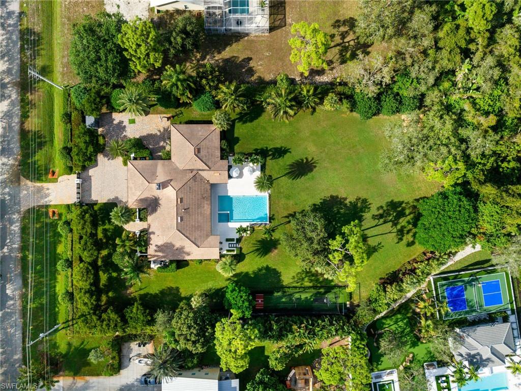 This updated estate home is nestled on 1.63 acres of beautifully manicured grounds, offering unmatched privacy and serenity in the heart of North Naples. X Flood Zone. One of the highest points in Naples, 17 FEET HIGH! Behind the gates, you will see a hard to find 5 bedroom 5.5 bath home sprawling 3800 sq/ft.  Wide-plank French oak flooring flows throughout the home, adding warmth and sophistication.  The primary suite is a private sun-filled retreat that opens through French doors to its own patio.   The outdoor living is elevated with a fully reimagined lanai and pool and spa area, lush tropical landscaping, and even a batting cage—the perfect blend of relaxation and recreation. Plenty of room for an addition or guest house. The climate-controlled garage features a new mini-split system and epoxy flooring (2024). Recent upgrades include: Andersen impact doors & windows (2020), additional mudroom,  tankless hot water heater, newer HVAC and plumbing systems (2023) New electrical panels (2023) City water connection.  Located within walking distance of Waterside Shops and just minutes from Mercato, the beach, and downtown Naples, this property combines luxury, privacy, and an unbeatable location—creating a true North Naples oasis.