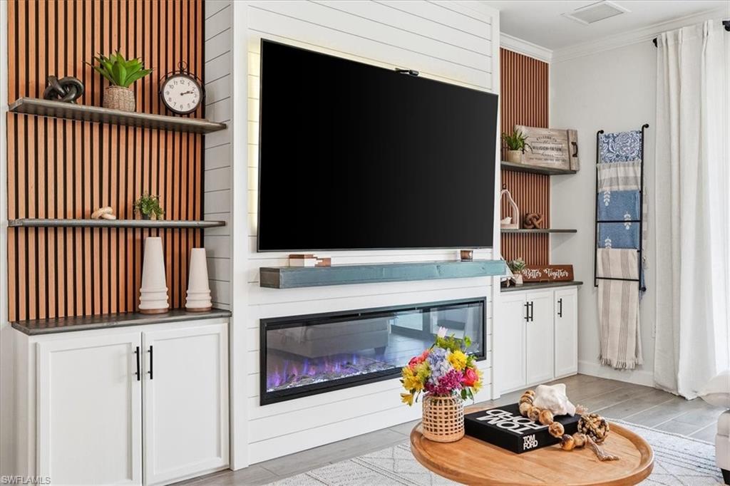 Tucked into the vibrant Verdana Village community, this exquisitely upgraded Amalfi model at 18656 Ives Drive proves you don't have to wait to build to own something truly special. With 4 bedrooms, a versatile upstairs loft, 3 full baths, and 2,606 square feet of impeccably finished living space, every inch tells a story of thoughtful craftsmanship. The current owners spared no detail. Custom wood-detail walls grace the entry, dining room, office, loft, and primary suite, while crown molding wraps the entire first floor. A striking entertainment build-out anchors the main living room with floating shelves and a fireplace, echoed by a second feature wall in the loft. The kitchen impresses with a gas range, quartz counters, abundant cabinetry, custom backsplash, and a shiplap-wrapped island, complemented by a stylish coffee bar with wine fridge. Carpet has been eliminated throughout—including the staircase—and matte black hardware ties the palette together. Just outside is a fully enclosed pool and spa retreat featuring color-changing LEDs, a tongue-and-groove wood lanai ceiling, and a custom outdoor fireplace built for evening gatherings. Fresh exterior paint, upgraded lighting, sealed pavers, and lush new landscaping complete the picture. Impact glass windows deliver peace of mind through any storm. Three bedrooms reside upstairs alongside the loft, while a fourth bedroom on the main level offers flexibility for guests. The location is equally compelling. Publix at The Shoppes at Verdana Village sits less than a mile away, with Miromar Outlets, Gulf Coast Town Center and Southwest Florida International Airport within a short drive. Residents enjoy a remarkable amenity center boasting an indoor sports complex with tennis, pickleball, and basketball, plus a fitness center and resort-style pool. This is move-in-ready Estero living, elevated by uncommon quality and finished with genuine care.