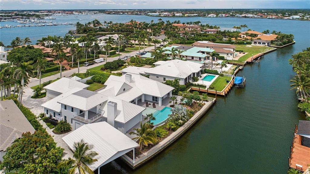 H.13236 - Built in 2016, on an oversized, south-facing lot with 153' of water frontage, this home is better than new! Reduced by $550K, now priced to sell! Truly a coastal masterpiece that blends clean lines with timeless styling, creating a distinctive home with the best of everything! Four separate bedroom suites + office, this home's 5,093 sq.ft. of living area is beautifully thought out w/stellar finishes, an open floorplan, towering ceilings and walls of glass letting in copious amounts of natural light. Great room design, gas fireplace, gourmet kitchen, top-of-the-line appliances, 3-bay collector’s garage. The lanai boasts 1500 sq ft of flexible, covered, outdoor entertainment space w/automated screens & shutters, featuring a full summer kitchen, gas grill, fireplace, pool-side lounge & bathroom. Tie up your boat in your private boathouse and throw the catch of the day on the grill! Gorgeous infinity edge pool, spa, deep water canal, just seconds from Naples Bay & the Gulf! Ultra luxurious private master suite w/separate bathrooms and huge closets. Just minutes to the beach  or famed 3rd Street shopping/dining. Call today, and live the life you deserve in Aqualane Shores!