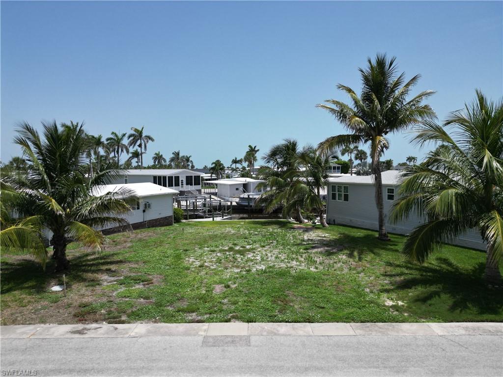 The creation of Bayside Estates dates back to 1968 which means the canals were dug and seawalls poured over 50 years ago.  Many of those seawalls have failed or are showing serious signs of wear and tear.  To replace a seawall today cost lots and lots of money.  That is money which may never be reclaimed later.  Much like putting in a swimming pool does not equate to a dollar for dollar increase in value, so it is with seawalls.  Therefore, the prudent buyer would be wise to seek out those properties where the former owner has already paid for a new seawall and due to circumstances is willing to take the financial hit on your behalf.  Their loss is your gain.  This Bayside Estates is one such lot.  A new seawall is in, the lot has been cleared and leveled, and is ready for a new home to be brought in.  Beyond being a good buy, this lot is simply gorgeous.  There are six lovely palm trees lining the perimeter of the lot giving you that tropical vibe we all desire.  Another valuable point is many vacant lots that were previously available for purchase in Bayside Estates have already been purchased and will most likely be built upon in the coming months. The inventory of vacant lots is running lower and lower as each lot transitions from available to sold. Therefore, if you're looking to acquire a desirable and valuable Bayside lot, look no further.      
Bayside Estates is the best kept secret of Fort Myers Beach. This incredibly active and friendly 55+ community is the crown jewel on the gulf coast. Bayside estates is only 2.5 miles to the beach and is accessible by either car or boat--right from either your driveway or private boat dock. A very popular activity is riding your electric bicycles to the beach for the day and visit the world-famous Jimmy Buffett’s Margaritaville. Just don't step on a pop-top!!. Nearly all of the major retail vendors are within a very short driving distance for ultimate convenience. For those who don’t know a lot about Bayside Estates, it is a very fun place to call home---some would even say it’s a mature person’s playground. Whether you want to play pickleball, tennis or bocce ball or hang out at the community pool, or simply cruise the hood in your golf cart, there is always something going on around here. People are friendly and you will be warmly welcomed.