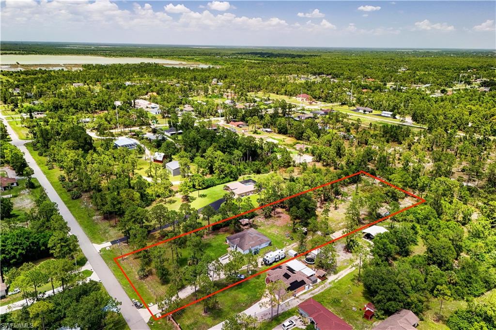 PRICED TO SELL! 2.27 ACRES & A BRAND-NEW ROOF COMING SOON! Searching for a Golden Gate Estates home with acreage, privacy,  and room for RVs, boats, and future expansion? This beautifully maintained 3-bedroom, 2-bath residence offers freedom and flexibility, all on 2.27 fenced acres in one of Naples' fastest-growing areas. The property is thoughtfully designed for those who need space, featuring DRIVE-AROUND ACCESS to the rear of the property, a 50-AMP RV HOOKUP and ample room recreational vehicles, a future guest house, workshop, barn, or additional outbuildings. Inside, you'll find a desirable split floor plan layout with VAULTED CEILINGS, TILE FLOORING THROUGHOUT (no carpet), newly added ELECTRIC FIREPLACE with custom accent-wall shelving in the living room, and freshly painted interior. The spacious kitchen is ideal for everyday living and entertaining, featuring GRANITE COUNTERTOPS, a tile backsplash, white cabinetry, a dedicated dining area, and an oversized WALK-IN PANTRY with exceptional storage. The FULLY RENOVATED GUEST BATHROOM has been beautifully updated with dual vanities, custom cabinetry, elegant mirrors, SHIPLAP ACCENTS, and a tiled tub/shower with a glass enclosure. The spacious primary suite offers a large WALK-IN CLOSET, and en-suite bathroom with dual vanities, granite countertops, and a walk-in shower, creating a comfortable private retreat. Additional improvements include updated electrical wiring, a NEW WATER FILTRATION SYSTEM, and a BRAND-NEW ROOF that will be installed prior to closing, providing valuable peace of mind for the next owner. Step outside to enjoy Florida living with a SCREENED LANAI, retractable awning, FIRE PIT, mature oak trees, and a custom-built CHICKEN COOP. The expansive FENCED PROPERTY provides plenty of room to add a pool, detached garage, or additional structures while still maintaining abundant open space. Conveniently located in the rapidly growing Orange Tree area, you'll enjoy close proximity to Big Corkscrew Island Regional Park, the Collier County Fairgrounds, new shopping and dining, highly rated schools, and everyday conveniences while still experiencing the privacy and tranquility that make Golden Gate Estates so desirable. No HOA. No restrictions. Endless possibilities. This is a rare opportunity to own a move-in-ready acreage property that offers space and unlimited potential in one of Naples' most sought-after rural communities. Schedule your private showing today and experience the freedom of Golden Gate Estates living! THIS PROPERTY QUALIFIES FOR A 1% LENDER INCENTIVE IF USING PREFERRED LENDER, INQUIRE FOR MORE DETAILS** Renderings that showcase furniture have been virtually staged.