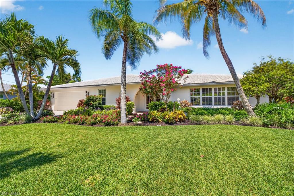 There are homes that impress, and there are homes that linger in memory long after the visit is over. The difference is often found in the details, the subtle nuances that quietly elevate a property from exceptional to irreplaceable. Along Sanibel Island’s desirable east end, this remarkable waterfront retreat is defined by those rare distinctions. Tucked away along the charming, tree-lined stretch of Anchor Drive, one of Sanibel’s sought-after streets, the setting alone is extraordinary. Unlike many island roads that simply end at the water, Anchor Drive transitions into a picturesque brick-paver lane leading to a private footbridge that gently crosses the canal and delivers residents directly to beach access beyond. It is a feature few properties on the island can claim, an effortless connection between boating and beach lifestyles, where morning bike rides to the Gulf and sunset visits along the sand become part of everyday life. Positioned at one of the desirable locations along the street, this exceptional residence commands a breathtaking setting where a serene mangrove-lined canal meets a wide sea walled canal, creating panoramic and breathtaking water vistas. With an impressive 180 feet of canal frontage, the property offers not only extraordinary privacy and scenery but also enhanced maneuverability, expanded dockage and direct boating advantages. The substantial private dock and lift can accommodate significantly larger vessels than most neighboring properties, delivering a yachter’s lifestyle with wonderful Gulf access. Surrounded by lush tropical landscaping and enveloped in complete privacy, the home itself has been beautifully reimagined through an extensive remodel that blends refined island elegance with relaxed coastal sophistication. Thoughtfully curated interiors are complemented by designer furnishings, inviting gathering spaces and richly appointed finishes throughout. Expanses of beautiful flooring guide you through multiple living and sitting areas designed equally for intimate relaxation and effortless entertaining. At the center of the home, a stunning chef’s kitchen with an expansive island serves as the natural focal point, seamlessly connecting the interiors to the spectacular outdoor setting beyond. Walls of impact glass draw the eye outward to the screened pool enclosure, tranquil waterways and swaying tropical landscape, creating a constant sense of connection to the island’s natural beauty. This is more than a waterfront home. It is a rare convergence of location, boating access, beach proximity, privacy and lifestyle, the kind of property whose value reveals itself not in a single feature but in the extraordinary way every element comes together.
