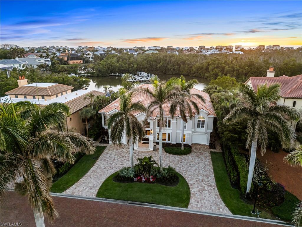 Beautiful Gulf-access estate perfectly nestled within the exclusive, double-gated Southport on the Bay in North Naples’ premier “Barefoot Beach” community, offering breathtaking Bay views. This coastal haven is a dream for beach and boating enthusiasts, with deeded beach access just a short walk away and direct Gulf access only 10 minutes from your boat dock and lift. Enjoy breathtaking sunsets with highly sought after Western exposure, also providing ideal sun on the spacious pool with the bay beyond. This residence offers 4 bedrooms + a den, 3.5 bathrooms, tile and wood flooring, soaring high ceilings, a cozy fireplace, a bar with a wine fridge, and ground floor flex space. Additional features include hurricane shutters, a private elevator, a 500 gallon buried propane tank, and an elevated generator for the second floor living area. The beautifully renovated chef’s kitchen boasts stunning quartzite countertops, custom white cabinetry, and top-of-the-line appliances, including a Sub-Zero refrigerator, Wolf double oven, and Wolf microwave. A breakfast bar adds convenience, while the eat-in kitchen, with its frameless picture window, frames picturesque Bay views. Step outside into your private outdoor oasis, complete with a summer kitchen including a grill, beverage cooler, and sink—ideal for al fresco dining. The expansive pool deck offers a salt water pool & spa, ample lounging areas, and a fenced yard perfect for pets. The primary suite is a true sanctuary, featuring private lanai access and a spa-like bathroom with dual vanities, a glass shower enclosure, and a soaking tub. Optional membership to the exclusive "Club at Barefoot" provides access to tennis, two restaurants, beachside food and beverage service, and more. Conveniently located near fine dining, RSW Airport, Mercato, and Waterside Shops, and just 15 miles from the renowned Fifth Avenue in Naples, this home is a true gem in the heart of Barefoot Beach.