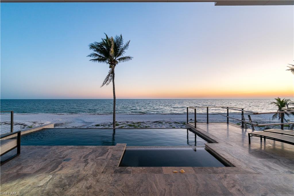 H10405     Direct Beachfront Home built in 2018 by the highly regarded Potter Homes. Perfectly located minutes to Mercato & North Naples’ amenities, this state-of-the-art beachfront masterpiece boasts the finest features, finishes & décor, with the Gulf of Mexico as the backdrop. Exceptional open floor plan with fully pocketing sliders to the beachfront entertainment deck with infinity edge pool & spa, outdoor kitchen with gas grill, fireplace & pool bath: seamless indoor/outdoor beachfront living. No details overlooked from the Gulf view chef’s kitchen with Thermador appliances, quartzite counters & adjacent walk-in bar, to the white oak hardwood floors & floating wood beam ceilings, to the Crestron smart home, lighting, and automation. Offered furnishings negotiable & decorated in a stunning coastal contemporary motif by the celebrated Freestyle Interiors. This 5,300+ sq ft estate includes a 2nd master/VIP suite, garage for 4+ cars & private elevator. Built to the most current & stringent codes with concrete block construction, Andersen hurricane impact windows, motorized screens + storm shutters & aluminum snap-clad metal roof system. Inside & out—a showcase of visionary design.
