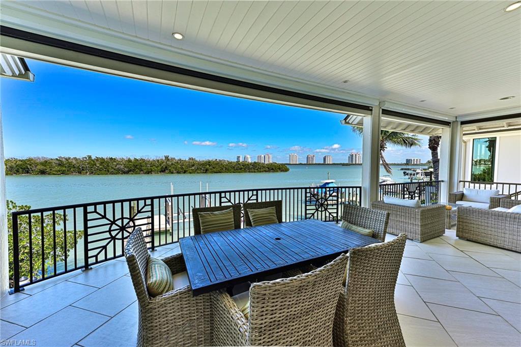 This timeless Coastal Island Style 3 story Bayfront home in the Carolands at Bonita Beach includes 7029 SQ FT of total living area and 3757 AC SQ FT, 4 bedrooms +den, 5 baths and turnkey decorator furnishings for a no hassle move in. The ultimate lifestyle awaits with turquoise water bay views from nearly every room, premier boating from your private dock with 14,000# lift where the Gulf pass is just minutes away, a convenient beach access to beautiful Bonita Beach at the entrance to the Carolands, and a swimming pool, spa and large summer kitchen/bar in a private tropical setting looking at wide, long water views. The main living level features wide & long bay views from it’s open floor plan where the kitchen, dining room and great room are all open to each other and to the wide covered lanai accessed by pocket sliding doors and enclosed by electric screens.  The designer kitchen with high quality stainless appliances including gas range, granite counter tops, custom tile backsplash continues seamlessly to the dining room that offers a bar with wine cooler in custom cabinetry.  The great room features a gas fireplace with large screen TV and a large sectional that can accommodate a large family.  Three guest rooms with en-suite baths and the powder bath complete the main level. The 3rd floor is comprised of only the master suite w/direct bay views,  sitting area & office, designer closet & beautifully designed & appointed master bath.  The lower level features the pool & spa complimented by a large shell-stone pavered deck that is perfect for private sunbathing or entertaining a large party.  Only the finest quality is found throughout including all impact doors & windows, standing seam metal roof, concrete pilings & siding, tile & hardwood flooring, custom cabinetry and millwork, plantation shutters & a private elevator to all floors. A rare find where the details of the home exteriors and the details of the homes interior are both exceptional. It is a short drive to Mercato & Coconut Point Malls, shopping, dining, entertainment, golfing, and RSW International airport plus there are new restaurants and more coming close by.