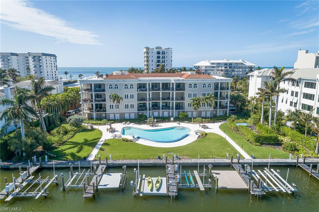 Welcome to private and secure luxury living on prestigious Gulf Shore Boulevard in this spectacular southwest corner penthouse at Bella Baia. Completely remastered by London Bay, this open-concept design emphasizes spaciousness, style and spectacular beach-to-bay views. Classic wood floors, plantation shutters and oversized moldings set a refined tone throughout the living areas. The kitchen features sleek custom cabinetry, a generous breakfast bar, mitered quartz countertops and top-of-the-line paneled appliances, making it a true culinary dream. Stylish living room features a custom built-in and ceiling details, which flow seamlessly into a large lanai space, perfect for enjoying the serene views and gentle coastal breezes. Retreat to the primary suite with expanded dual walk-in closets, large shower and free-standing tub adorned with striking mitered quartz countertops. A private two-car garage, boat slip and gated beach access for direct enjoyment of the sandy shores complete the property.
