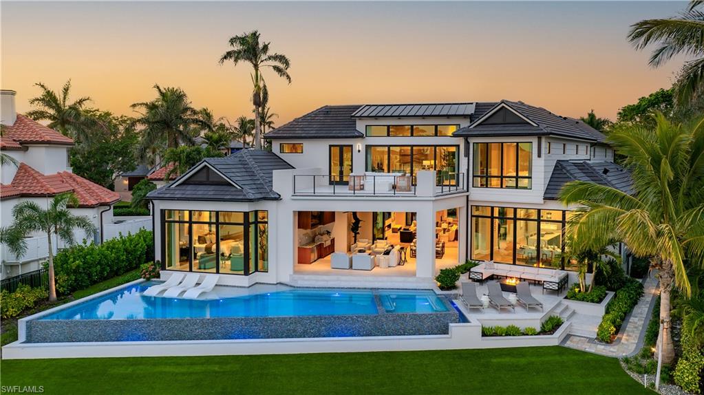 This stunning new construction home in the prestigious Port Royal neighborhood blends modern elegance with serene waterfront views of Hidden Bay. Crafted by Kukk Architecture & Design and built by Wilbrett Construction, it features exquisite interiors by Adelyn Charles Interiors and offers a sophisticated yet relaxed living experience. The floor plan balances spacious communal areas with private retreats. The primary suite on the main floor boasts posh walk-in closets, a spa-like bath, and an executive study. Four guest ensuites on the upper floor and a large bonus room with a wet bar and a second laundry area ensure comfort. Guests will enjoy dolphin sightings and boat views from the open-air balcony. Premium finishes abound, including quality bespoke cabinetry, European hardwood floors, and top-of-the-line Wolfe, Sub-Zero, and Miele appliances. Built with superior techniques, the home features full concrete construction, Andersen impact windows and doors, an elevator from the garage level, remote-controlled screens and shutters, and a whole-house generator. Car enthusiasts will appreciate the oversized three-car garage with room for lifts and an additional bay for a low-speed vehicle. The resort-style infinity pool, spa, covered lanai, summer kitchen, firepit, and lounge area create a perfect outdoor haven. Eligibility for an exclusive 
Port Royal Club Resident Membership is included.