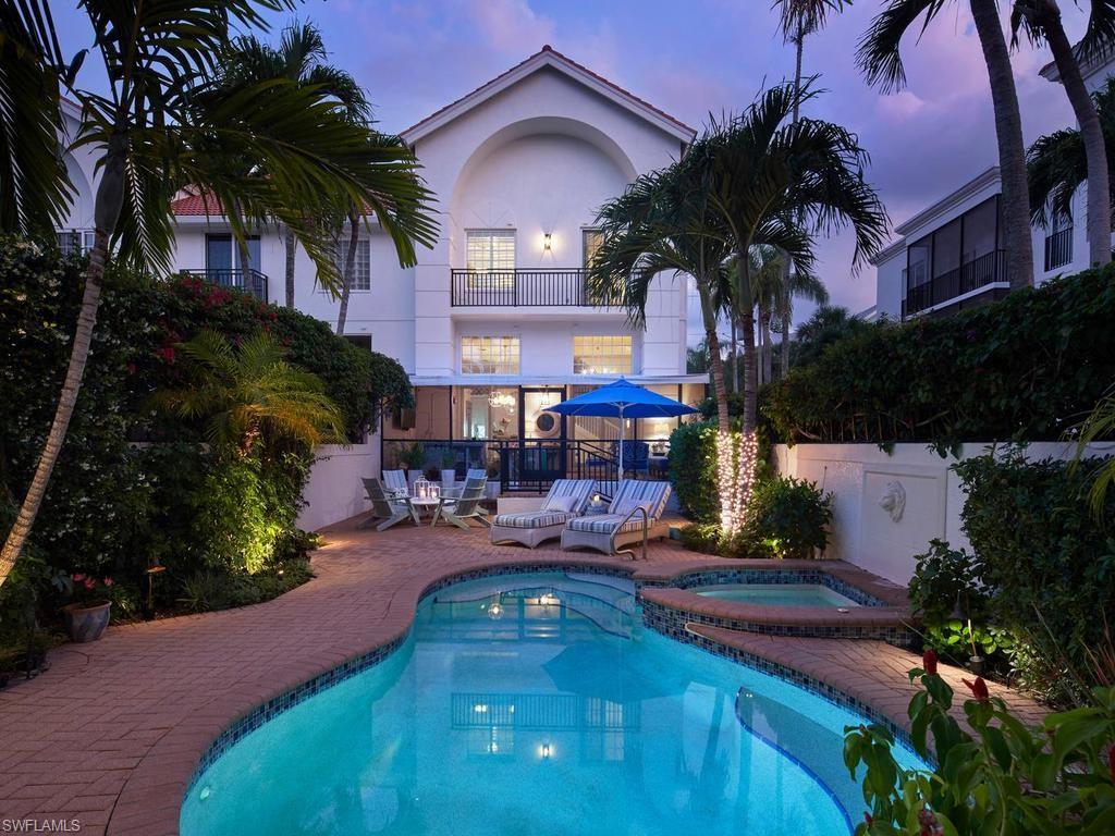 Tucked within the intimate Isla Mar community in the heart of Old Naples, this end-unit residence lives like a private coastal retreat. Spanning approximately 2,280 square feet, the multi-level floor plan is filled with natural light and defined by crisp white interiors, shiplap detailing, and thoughtfully curated coastal finishes throughout. The open-concept kitchen serves as the centerpiece of the home, featuring an oversized island with seating, custom cabinetry, and designer tile accents, seamlessly connecting to multiple living and dining spaces ideal for both everyday living and entertaining. Sliding doors and expansive windows create a strong indoor-outdoor connection, opening to a series of inviting spaces. The primary suite offers a comfortable and private setting with a well-appointed bath including dual vanities, soaking tub, and separate shower. Additional guest bedrooms provide flexibility for family and visitors. Outdoor living is a defining feature, with multiple balconies, a screened lanai, and a private courtyard designed for year-round enjoyment. The gas-heated pool and spa, water feature, and lush tropical landscaping create a quiet, resort-like atmosphere rarely found in a condominium setting. Additional highlights include a private elevator, two-car garage, impact-resistant windows and doors, and a dedicated laundry room. Ideally located just four blocks to the Gulf beaches and moments to the shops and dining of Third Street South, this residence offers a rare combination of privacy, space, and walkable Old Naples living.