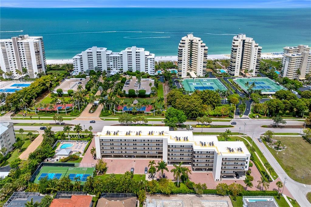 Offering beach access just across the street, this refined residence delivers the rare combination of coastal convenience, flexibility and elevated comfort in one of Marco Island’s sought-after beachfront communities. In the Grandview, this two-bedroom, two-bath residence includes one assigned carport space and showcases effortless indoor-outdoor living with a screened, covered balcony designed for year-round enjoyment. Electric storm shutters provide added peace of mind while preserving the relaxed coastal lifestyle. Weekly rentals are allowed, offering excellent flexibility for personal use and potential rental income. Recently painted throughout, the residence also features new contemporary vinyl plank flooring in both bedrooms, while timeless tile flooring runs throughout the main living areas, creating a clean, cohesive aesthetic that enhances the bright natural light filtering through expansive glass sliders. Custom mirrors add a sophisticated touch throughout the residence. The living room is designed for comfort and entertaining, featuring a ceiling fan, generous natural illumination and seamless access to the screened balcony that extends the living space outdoors. The adjacent dining area flows naturally into the living room, ideal for casual gatherings or formal entertaining. The kitchen is thoughtfully appointed with recessed lighting, custom cabinetry, a breakfast bar counter, and a full suite of appliances including a microwave, electric range, dishwasher, and refrigerator/freezer, blending function with understated elegance. The primary bedroom is a serene retreat, offering abundant natural light and a ceiling fan for year-round comfort. The en-suite bath features a fully enclosed walk-in glass shower, creating a spa-like setting for daily relaxation. A well-appointed guest bedroom also includes a ceiling fan, providing a comfortable and inviting space for visitors. The guest bath, off the hallway, features a convenient shower and tub combination. A dedicated laundry area with washer and dryer adds everyday practicality. Residents enjoy an exceptional suite of resort-style amenities, including a community pool and spa/hot tub, barbecue and picnic areas, beach access, bike storage, extra storage options, pickleball, and tennis courts. This is coastal living at its most effortless, where every detail is designed to complement the rhythm of island life.