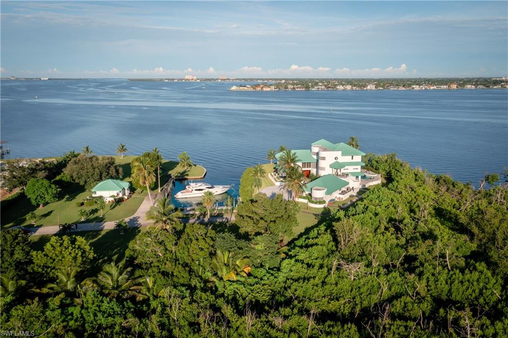 The Crown Jewel of Southwest Florida! 

An irreplaceable private waterfront compound of rare pedigree — the only estate in Southwest Florida boasting its own grandfathered-in "Super Yacht Marina", capable of accommodating vessels exceeding 125+ feet directly on-site. This 5.73-acre peninsula sanctuary is a landmark of distinction, embracing more than 1,000 feet of shoreline with sweeping, cinematic 9-mile vistas stretching from the skyline of Fort Myers to the luminous sunsets over Sanibel.

Approached by a quarter-mile gated drive framed by sculpted palms and custom iron castle gates, the property opens to an all-concrete contemporary residence, recently reimagined in elegant white. The home’s minimalist architecture offers soaring walls ideal for art display, seamless indoor-outdoor flow, and breathtaking water views from nearly every room. For ultimate convenience, an elevator is available to smoothly connect access to all floors of the main residence. Six bedrooms, five and a half baths, and multiple living and entertaining areas define a residence as refined as it is resilient.

The estate’s non-duplicable Super Yacht Marina is its defining masterpiece — a deep-water yacht basin with approximately seven feet of depth at mean low tide, capable of accommodating multiple large vessels with full-service infrastructure. Power and water are on-site, and an air-conditioned guest residence sits directly alongside the marina, complete with a full kitchen, bath, and its own generator. This versatile space serves as the ultimate captain’s quarters, guest retreat, or private waterfront lounge — a seamless extension of the estate’s rare maritime luxury.

Beyond the existing residence, the land itself offers extraordinary potential: the opportunity to create additional panoramic-view homesites through subdivision into two or three parcels, or to add luxury amenities such as sport courts, pavilions, or wellness gardens. The newly installed seawalls, manicured lawns, and lush tropical landscaping create an irreplaceable private resort atmosphere.

Hidden from view behind mangrove-lined shores yet only moments from the Gulf of Mexico and SW Florida International Airport, this estate is known to every mariner navigating the Intracoastal toward Fort Myers — the iconic white mansion at the bend of the waterway.

More than a home, this is a statement of legacy — the Crown Jewel of Southwest Florida — for the discerning few who seek the rarest of luxuries: privacy, permanence, and perfection.
