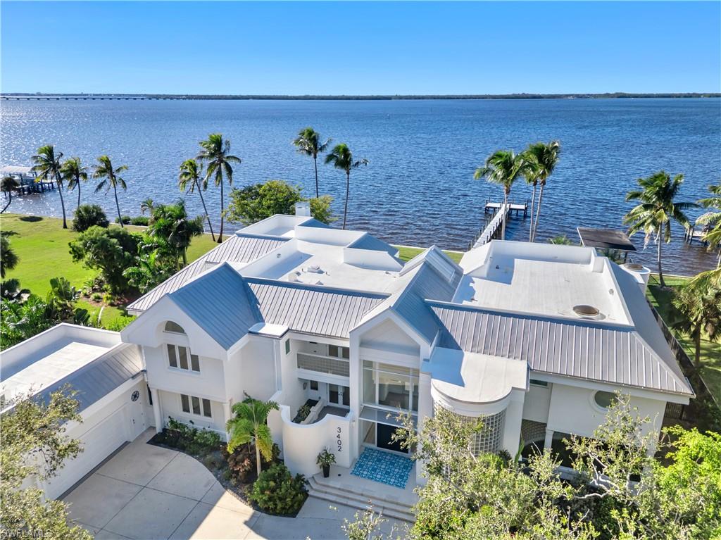 Located just off historic McGregor Boulevard, this elevated, all-concrete riverfront estate offers a rare combination of scale, security, and privacy along the Caloosahatchee River. Set on a private, oversized parcel and framed by new fencing and mature, thoughtfully enhanced landscaping, the property feels intentionally secluded, yet remains only minutes from downtown Fort Myers and the vibrant River District. Spanning nearly 8,700 square feet of living space, the home has been extensively upgraded and thoughtfully maintained. Highlights include a newer roof, upgraded mechanical systems and appliances, new flooring, impact-rated windows and doors throughout, soaring ceilings, and expansive living areas that feel both impressive and highly livable. Abundant natural light fills the interior, enhanced by skylights that reinforce the home’s open, forward-thinking design. Outdoor living is exceptional, with multiple balconies and lanai spaces perfectly positioned to capture breathtaking river views and unforgettable sunsets. A standout feature is the rare covered boathouse basin, an ideal solution for protected boat storage. Storage throughout the home is equally impressive, featuring extensive custom closet systems and a substantial four-car garage designed for both daily use and serious vehicle storage, ideal for car enthusiasts. The waterfront setting truly defines the estate. The pool and lanai are oriented directly toward the river, delivering unobstructed water views with no visual distractions. Approximately 150 feet of river frontage, a brand-new seawall, and a new dock create a fully turnkey waterfront experience. Elevated, substantial, and ahead of its time, this fortress-like riverfront estate is positioned within one of the area’s most established waterfront corridors, just moments from historic downtown Fort Myers, the Edison & Ford Winter Estates, exceptional dining, nearby schools, and everyday conveniences. This is a lifestyle and location that continues to stand the test of time.