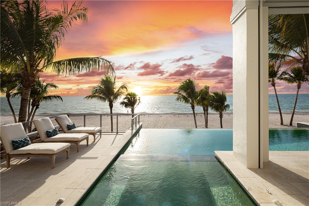 DIRECT BEACHFRONT MASTERPIECE WITH AN ELEVATED POOL/SPA! Enjoy the sugar white sands and turquoise waters of the Gulf as your daily backdrop. Custom built by the renowned Potter Homes, this home showcases superior craftsmanship and thoughtful design with the finest finishes throughout, including rich white oak flooring and soaring custom ceilings accented with wood beams and paneling. Built like a fortress, this home is built with a metal roof, hurricane impact windows and sliders throughout, and electric storm shutters. The expansive open-concept floor plan is ideal for entertaining, highlighted by fully pocketing sliders that create seamless indoor-outdoor living and open to the RARE ELEVATED POOL DECK. The resort-style outdoor living area offers an infinity-edge pool and spa, summer kitchen, and outdoor fireplace—perfectly positioned to enjoy breathtaking, unobstructed Gulf views. Spanning 4,646 square feet under air, the home includes five bedrooms, five full baths, and an oversized garage with space for six or more vehicles. The gourmet chef’s kitchen boasts quartz and granite countertops, crisp white cabinetry, an ocean-blue backsplash, an oversized eat-in island, a walk-in pantry, and top-of-the-line Thermador appliances. Adjacent to the kitchen, the formal dining area is enhanced by a beverage bar with a built-in wine refrigerator and elegant glass-enclosed cabinetry. The luxurious primary suite is a true retreat, offering panoramic Gulf views, access to a private open-air balcony, dual large walk-in closets with custom built-ins, and a spa-like bath with dual vanities, a soaking tub, and an expansive walk-in shower. Additional highlights include a private elevator and a Crestron smart-home automation system with electric shade and shutter controls. Ideally located within walking distance of top beachfront dining and just minutes from Mercato, The Promenade, Waterside Shops, Coconut Point, 5th Avenue, and the International Airport nearby. This home is the pinnacle of beachfront living.