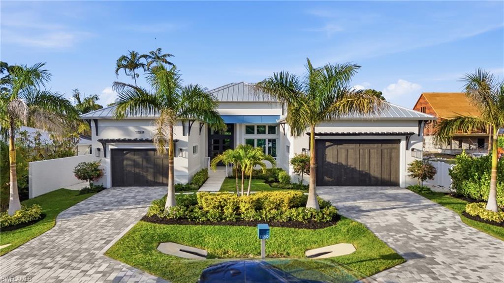 This coastal contemporary located exactly 1 mile to the beach in Naples.

This 4 bedroom + den, 4.5 bath luxury residence offers 3,300 square feet under air and is positioned for both full-time living and effortless seasonal use. Bike to the beach, walk or ride to organic markets and breakfast cafés, and reach downtown Naples in approximately 7 minutes. Close to medical facilities, shopping, dining, and everyday conveniences while privately situated on a quiet street.

Designed with elevated specifications throughout, this home prioritizes performance, efficiency, and long-term durability.

The gourmet kitchen is fully equipped with a premium appliance package including a Wolf range, Sub-Zero refrigerator/freezer, dual Cove dishwashers, Sub-Zero wine and beverage refrigerator, Miele built-in coffee system, and a Zip integrated carbonated, chilled, and instant hot water dispenser.

Energy-efficient construction includes:
• High R-value spray foam insulated attic
• Rigid foam insulation within concrete block walls
• Energy Star appliances
• High SEER HVAC systems
• Variable speed pool pumps
• LED lighting throughout
• Impact-rated hurricane windows and doors
• Propane for pool heating, domestic hot water, and cooking

Ceiling heights are 12 feet or higher throughout, with dramatic 16-foot ceilings in the foyer and den.

The great room features real white oak ceiling beams, integrated lighting detail, wet bar with dual drawer wine and beverage refrigeration, and pocketing impact-rated sliding doors for seamless indoor-outdoor flow.

The lanai is finished with 1.25-inch marble decking, built-in BBQ and sink area, fire pit, and an outstanding pool with glass tile, sun shelf, spa, high BTU gas heater, and auto-fill/auto-leveling system.

Garages offer rare 14 and 16-foot ceiling heights and can accommodate lifts for up to six vehicles plus a golf cart. Insulated block construction, spray foam roofing, and epoxy floors help maintain cooler temperatures.

Smart home automation includes 360-degree security cameras, integrated speaker system with streaming capability throughout the home, garages and lanai, CAT-6 wiring and coaxial in every room, and multiple wireless access points.

Engineered hardwood flooring runs seamlessly throughout with zero transitions into tiled bath areas.

The primary suite features a tray ceiling with custom lighting detail, generous walk-in closets, and quality stone and vanity finishes.

Professionally landscaped grounds include mature palms, landscape lighting, artificial turf and shell hardscape for minimal maintenance, fencing, and privacy plantings.

A 500-gallon propane tank services pool heat, Wolf range, BBQ area, and hot water systems.

A rare combination of proximity to the beach, new construction quality, energy efficiency, oversized garages, and thoughtful upgrades throughout.