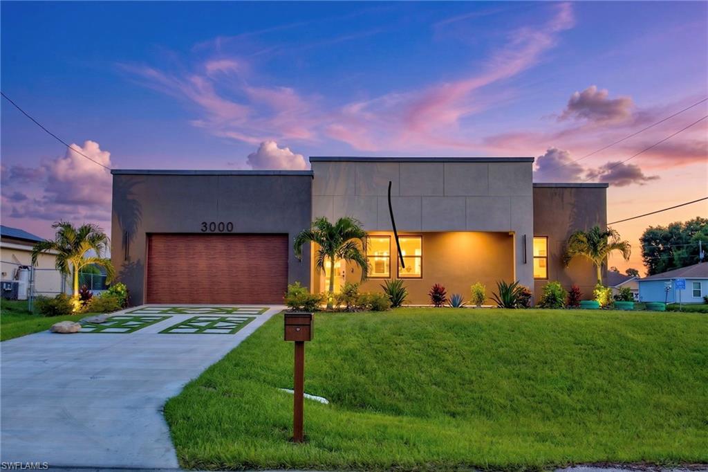 Move-in-ready modern residence with bold architectural lines, sleek finishes, and thoughtful design throughout. This newly built contemporary home features full-home polished porcelain tile, impact-rated windows and doors, and an open-concept living area anchored by a custom media feature wall and a designer kitchen with a waterfall island. Expansive sliders connect the interior to a covered lanai and large, landscaped yard, creating an effortless indoor-outdoor lifestyle in Cape Coral.  

**Features & Upgrades**

- New construction contemporary design with flat-roof elevation and contrasting stucco  
- Large-format polished porcelain tile flooring throughout the entire home  
- Impact-rated windows and doors with black-framed modern styling  
- Custom living-room feature wall with textured vertical panels and marble-look inset  
- Chef-inspired kitchen with waterfall-style island and marble-look surfaces  
- Full-height white shaker cabinetry with modern black hardware and deep storage  
- Black undermount kitchen sink with high-arc faucet and backyard view  
- Designer hexagon pendant lighting over the dining area  
- Spacious primary suite with private, spa-style bath  
- Walk-in primary shower with marble-look wall tile, frameless glass, and black fixtures  
- Guest bath with soaking tub/shower combo and full-tile surround  
- Consistent modern look: black ceiling fans, minimalist baseboards, high-contrast fixtures  
- Covered lanai with ceiling fan and recessed lighting for outdoor living  
- Expansive backyard with lush lawn, young trees, and privacy fencing—ideal for future pool  
- Geometric concrete-and-turf driveway with wood-look garage door and tropical landscaping  
- Finished two-car garage with clean, textured flooring and bright lighting