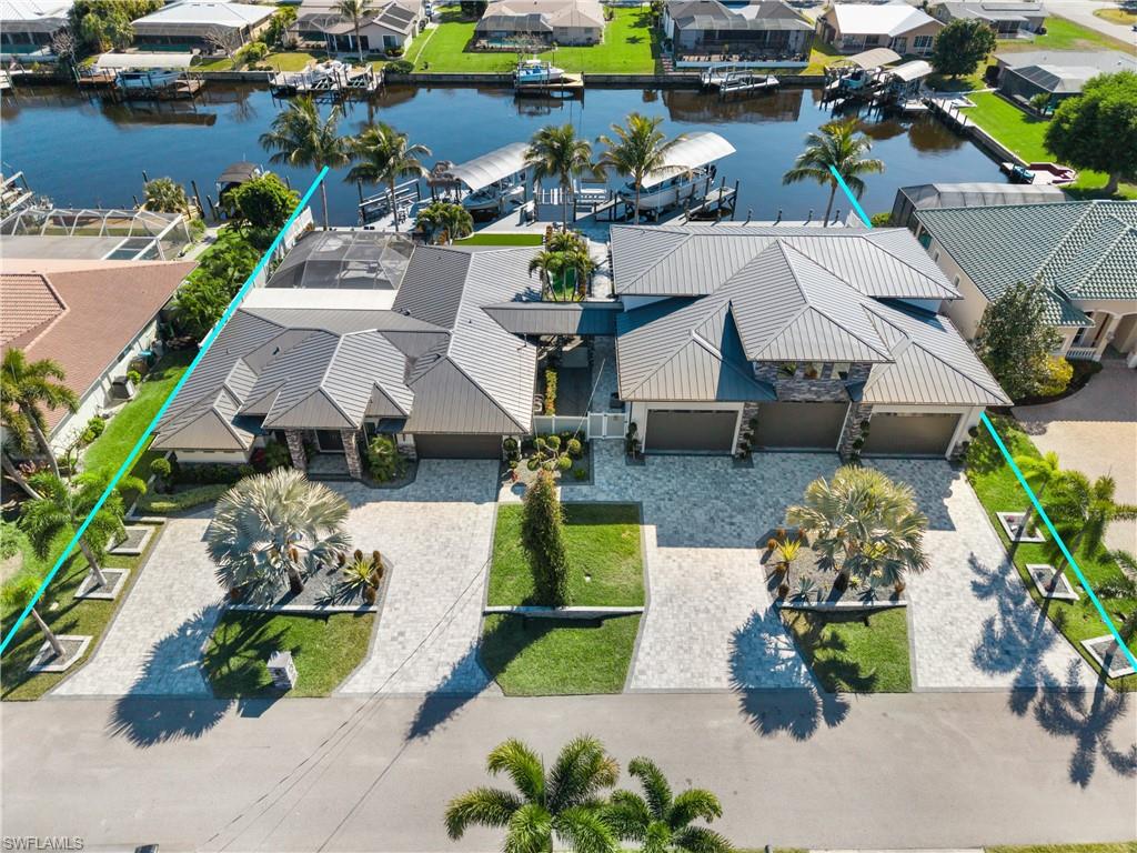 Introducing a truly one-of-a-kind waterfront compound where modern luxury living meets unmatched storage, recreation, security, and boating capabilities. Rarely does a property offer this level of versatility — featuring a stunning primary residence, a separate showroom-style garage capable of accommodating up to 19 vehicles, an exceptional dock system with four boat lifts rated at approximately 4,500 lb, 16,000 lb, 28,000 lb, and 30,000 lb, and a fully upgraded security system with extensive coverage and dramatic nighttime lighting. The main home showcases contemporary coastal design with an expansive open-concept layout built for both everyday comfort and effortless entertaining. The great room centers around a custom media wall with linear fireplace and flows seamlessly into a chef’s kitchen featuring a massive waterfall island, sleek cabinetry, premium appliances, and designer lighting. The spacious primary suite offers a private retreat with a spa-like bath, while additional bedrooms provide comfortable accommodations for family and guests. A resort-style screened lanai with pool, spa, and covered seating areas completes the home’s indoor-outdoor lifestyle. The detached garage structure is truly extraordinary — a collector’s dream with soaring ceilings, professional-grade lifts, and showroom-quality finishes. Above, a fully finished upper level includes a spacious living area with full kitchen, bar, and two bedrooms, creating ideal guest quarters, extended-family accommodations, or a private retreat separate from the main home.
Outside, beautifully landscaped grounds feature expansive paver walkways, maintenance-free turf areas, and multiple waterfront seating spaces. The substantial dock system and covered gathering areas make entertaining effortless, while the advanced security features and strategically designed exterior lighting provide both peace of mind and a stunning presence after dark. This is more than a home — it is a private waterfront estate designed for those who want it all: luxury living, serious garage space, premier boating facilities, enhanced security, and a lifestyle few properties can offer.