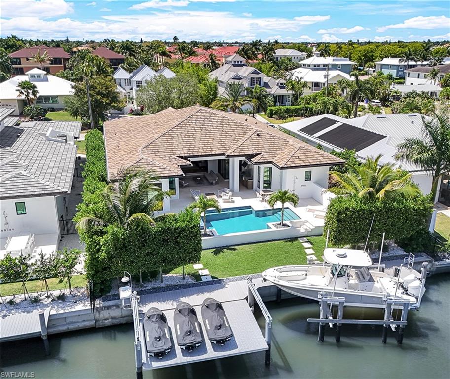 Don't miss this rare opportunity for waterfront living at its finest, just minutes from downtown Naples!!!  This flowing floor plan custom-built in 2021 boasts 4 spacious bedrooms including 4 en-suite luxurious baths!! Every inch exudes opulence, from the grand entrance to the serene outdoor oasis featuring lush landscaping and a sparkling uncaged open pool. Inside, European white oak plank flooring and post-and-beam cypress ceilings set a captivating tone. The chef's kitchen boasts top-of-the-line Thermador appliances and quartz countertops, perfect for culinary endeavors. Retreat to one of four bedrooms, each with ensuite baths and walk-in closets, including a luxurious owner's suite with an extra large luxurious bath boasting a dual vanity, walk-in shower, and a separate soaking tub, as well as, a massive closet with custom shelving, hanging racks, and drawers. Outside - a saltwater pool, outdoor kitchen, and fireplace await, while boating enthusiasts will delight in the canal access with a boat and jet ski lift. Furnished with Restoration Hardware designed decor and equipped with smart home features - All Included! Luxury meets functionality in every aspect of this home, from the custom-designed ceilings and millwork to the motorized shades and Lutron lighting system. You can rest assured here - the whol­e hous­e gen­er­a­tor and su­pe­rior el­e­va­tion has kept this prop­erty high and dry.