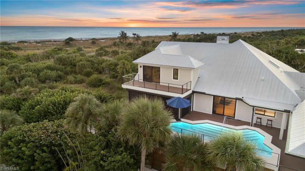 A rare offering on Sanibel’s exclusive Joewood Drive, this completely reimagined Gulf-front estate embodies understated coastal luxury and meticulous craftsmanship. Set within the private Gulf Ridge community, the home has been rebuilt from the ground up, featuring a new standing-seam metal roof, impact-rated glass throughout, and a whole-house generator for complete peace of mind. Designed for effortless island living, the residence offers soaring ceilings, an open-concept layout, and panoramic Gulf views that flood the interiors with natural light. The elevated pool and deck flow seamlessly from the main living level, creating a perfect indoor-outdoor experience for entertaining or quiet reflection. A private path leads from the home to a vast stretch of pristine beach, where shell-covered shores and breathtaking sunsets capture the essence of Sanibel’s natural beauty. Additional highlights include a private elevator, a chef’s kitchen with custom cabinetry and professional-grade appliances, and designer furnishings throughout. A stand-alone two-car garage provides added storage and flexibility for vehicles, golf carts, or beach gear. Every space, surface, and system has been thoughtfully curated for beauty, comfort, and durability. Move-in ready and masterfully rebuilt, 5079 Joewood Drive represents one of Sanibel Island’s finest Gulf-front homes, where refined design meets relaxed island living amid one of Florida’s most extraordinary coastal settings.
