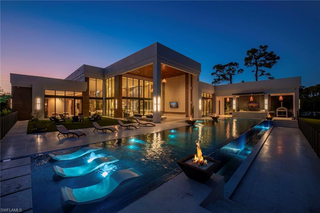 Villa Luminara, where light meets luxury, is a one-of-a-kind architectural residence designed to capture natural light, organic interiors, and exceptional outdoor living, creating a private resort environment rarely found in residential homes. Spanning 10,553 total square feet with 7,890 square feet under air across a single level, the home presents a modern exterior while the interiors embrace a warm, natural palette that feels upscale while remaining relaxed and inviting. With soaring 22-foot ceilings in the main living areas and expansive glass throughout, natural light fills the home while framing views of the surrounding landscape and creating a new definition of indoor-outdoor living.
Designed for both everyday living and entertaining, the outdoor environment feels like a private resort. A breathtaking 90-foot saltwater pool anchors the space, complete with a rain waterfall at the bar and four fire bowls with cascading water features. Entertain with ease using the outdoor firewood grill and pizza oven, or relax in a setting designed to feel like a permanent retreat where there is truly little reason to ever leave home.
At the heart of the residence is a chef’s kitchen unlike any other, custom designed with professional-grade appliances including a Wolf and Sub-Zero gas range, Pavoni coffee machine, and additional refrigeration. The kitchen is complemented by a display kitchen, bar, and walk-in wine room, creating a culinary environment designed for both daily living and entertaining. Gas, induction, and electric cooking options provide exceptional versatility.
The home offers five bedrooms and expansive living spaces that balance impressive scale with warmth and sophistication. Custom details are present throughout, including bespoke finishes, imported lighting, and thoughtful design elements that enhance the organic and natural feel of the interiors.
Additional features include a four-car garage with EV chargers and lift capability, impact-resistant doors and windows, a 60KW whole-house generator, two tankless water heaters, and a 1,000-gallon propane tank.
All set on 1.18 private acres in the heart of Pine Ridge Estates, this residence offers a rare combination of architecture, light, and lifestyle, while still being in close proximity to Waterside Shops, the beach, Mercato, and downtown Naples so you are always just moments from the best of Naples.