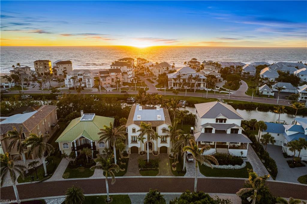 Exquisitely renovated & coastal contemporary Gulf-access estate nestled within the exclusive, double-gated Southport on the Bay in North Naples’ highly sought-after Barefoot Beach community. With coveted WEST exposure, you’ll enjoy SPECTACULAR SUNSETS and PRIME SUN over the RARE ELEVATED POOL & POOL DECK! A true paradise for boaters and beach lovers, this property boasts direct Gulf-access in minutes (no bridges) and is just a short 5-minute walk to the pristine shores of Barefoot Beach. Designed for the ultimate waterfront lifestyle, this home features a private boat dock and a new boat lift with a canopy. Inside, you’ll discover 4 spacious bedrooms, a den, a large bonus room, 4 bathrooms, 4 half baths, a private elevator, versatile ground-floor flex space, and a garage that accommodates 6+ cars. This residence showcases a coastal contemporary design with an open, light-filled interior, soaring ceilings, and wood-look flooring. Additional features include a new flat roof (2022), hurricane impact windows and sliders, and hurricane shutters. Step outside to your personal outdoor haven, complete with an elevated pool and spa, a cozy fireplace, pool bath, and a summer kitchen designed for the perfect al fresco dining experience. The stunning chef’s kitchen boasts white quartz countertops, sleek white cabinetry, white tiled backsplash, abundant storage, high-end appliances, and an adjacent wet bar—perfect for entertaining. The expansive primary suite, located on the main floor, features private access to the pool deck, as well as a spa-like bathroom with dual vanities, a generous shower with a rainfall showerhead, and a separate soaking tub. Upstairs, you'll find three additional bedrooms, a den, and a bonus room complete with a wet bar and beverage cooler, along with multiple balconies offering stunning water views. This private retreat is perfect for hosting guests or simply enjoying your own space. Optional membership to the exclusive "Club at Barefoot" provides access to tennis, two restaurants, beachside food and beverage service, and more. Conveniently located near fine dining, RSW Airport, Mercato, and Waterside Shops, and just 15 miles from the renowned Fifth Avenue in Naples, this home is a true gem in the heart of Barefoot Beach.