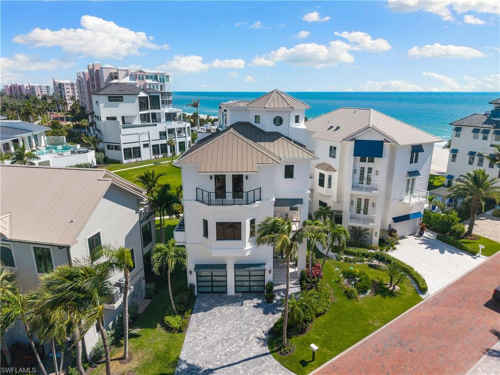 COMPLETELY RENOVATED STATE-OF-THE-ART BEACHFRONT MASTERPIECE LOCATED IN COLLIER COUNTY’S PREMIER “BAREFOOT BEACH” COMMUNITY! Nestled within the highly coveted Beach Gardens community, this remarkable residence offers unparalleled views of the pristine sugar-white sands and turquoise waters of the Gulf, with private beach access just steps away. Spanning an impressive 4,478 square feet under air across four levels of luxurious living space, this exceptional property features a private elevator, 4 bedrooms + den, 3.5 baths, versatile ground-floor flex space, stunning white oak flooring (2024), elegant white wood-paneled tray ceilings, smart home automation with voice-controlled features, and a Sonos sound system. This home is built with concrete block construction, 2018 metal roof, hurricane-impact windows and doors throughout, 3 new HVACs (2024), 2 new water heaters (2024), buried propane tank (2024), and new garage doors (2024). The main living level showcases a stunning chef’s kitchen appointed with quartz countertops, custom modern cabinetry, new premium appliances including a gas range and wine refrigerator, a butler’s pantry, and an oversized island with ample seating — ideal for entertaining. Step outside to the open-air balcony and take in the breathtaking panoramic Gulf views. At the top level of the residence, an expansive rooftop sun deck features generous lounging areas, a gas fire pit, and a summer kitchen complete with a stainless steel flat top grill and Green Egg smoker — creating the perfect setting to entertain guests while enjoying spectacular sunsets over the Gulf. The stainless steel cooktop and rooftop fire pit are conveniently piped directly to the buried propane tank, eliminating the need to haul propane tanks. An aluminum commercial-grade pergola is also scheduled to be constructed on the rooftop deck in June, further enhancing the exceptional outdoor living experience. The primary suite serves as a private sanctuary, featuring elegant French doors that open to your own Gulf-front balcony, along with a spa-like bath complete with dual vanities, a separate soaking tub, and a spacious glass-enclosed shower with multiple shower heads. The Beach Gardens community is surrounded by lush tropical landscaping and offers a beautiful resort-style pool. Optional membership to the exclusive Club at Barefoot Beach provides access to tennis courts, two restaurants, and beachside food and beverage service. Ideally located near fine dining, Southwest Florida International Airport, Mercato, Waterside Shops, and Fifth Avenue South, this extraordinary property represents the pinnacle of luxury beachfront living in Barefoot Beach.
