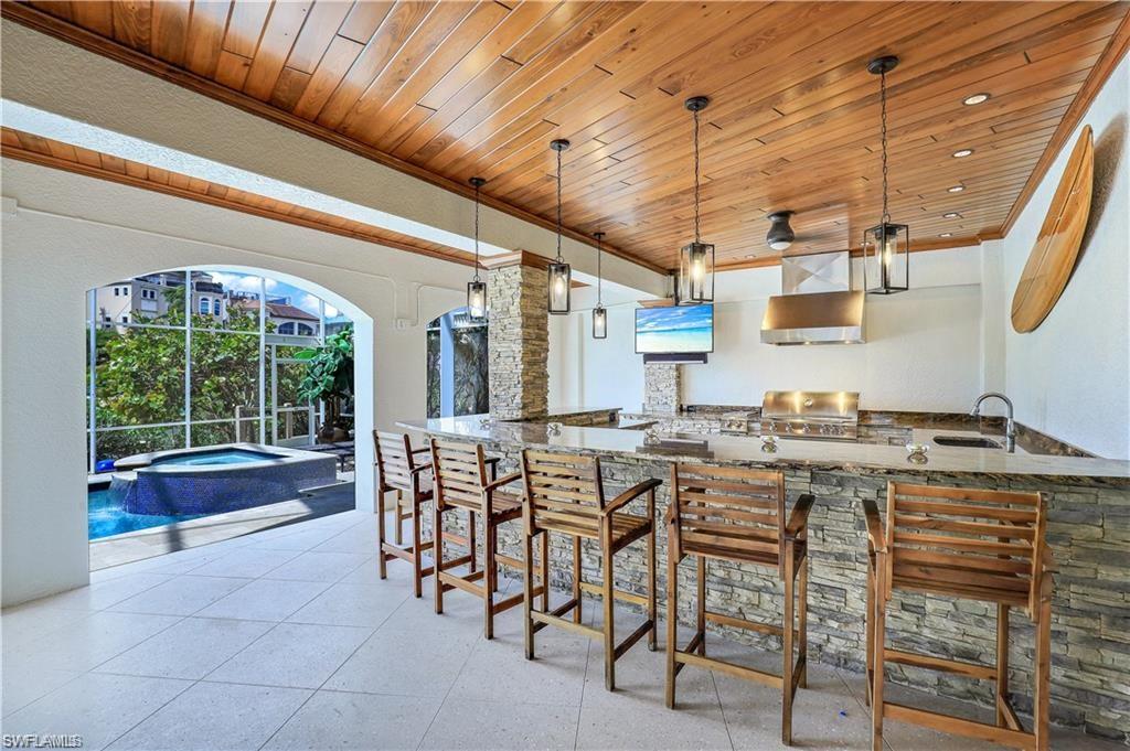 Welcome to this waterfront home in Southport, nestled in the renowned Barefoot Beach. Experience the allure of this stunning residence with spacious interiors, a private pool with a hot tub, boat dock, and lift, and newly landscaped surroundings. Enter through the dramatic 2-story foyer to discover a gourmet kitchen and adjoining family room, perfect for entertaining. A formal dining room adds elegance, while the lanai offers a panoramic pool and bay views. Unwind in the game room or by the fireplace in the formal living room. Thrill guests with Gulf boat rides and enjoy the pool, hot tub, and outdoor kitchen with BBQ, wine cooler, granite counters, and a big screen TV. This 4-bedroom waterfront home provides great entertaining space, a reading room/office, & everything you need for an active Florida lifestyle. Located within walking-distance of world-famous Barefoot Beach, this home is calling your name. Barefoot Beach is an exclusive gated beachfront community perfectly situated between Naples and Fort Myers in close proximity to world-class dining, upscale shopping, & phenomenal medical facilities. Don't miss this opportunity for coastal living at its finest!