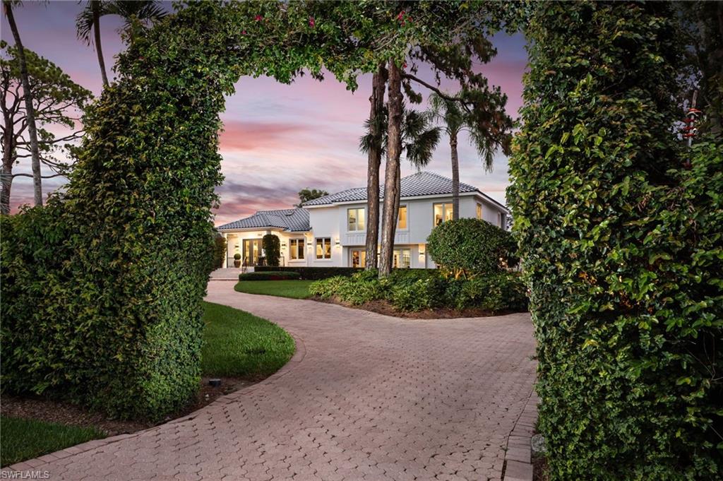 664 Hickory Road is the kind of Naples estate buyers whisper about—but rarely see hit the market. Set on 2.25 acres of fenced and gated privacy just minutes from the Gulf, this 5-bedroom, 5-bath, 4,332-SqFt residence has been completely transformed, delivering a crisp, modern aesthetic on a homesite no one can find. A long, sweeping drive curls through lush landscaping and sets the tone for what’s to come: a striking white façade with elegant metal railings, fresh tile rooflines, and walls of glass that glow at dusk. Inside, beamed ceilings, wide-plank wood flooring, and a soft neutral palette create a backdrop that’s both sophisticated and warmly livable. The open great room, dining room, and chef’s kitchen flow together, framed by oversized windows, skylights, and French doors that draw your eye to the pool and grounds. The kitchen features an oversized island, sleek quartz counters and custom cabinetry, all anchored by stylish pendant lighting and abundant natural light. Adjacent living and dining spaces allow guests to spread out, with indoor/outdoor connectivity that makes entertaining effortless. The owner’s suite is a retreat: a sprawling bedroom with sitting area and home office niche, serene garden views, designer lighting, walk-in closet, and spa-inspired bath. Additional guest suites and flexible family spaces give everyone room to breathe, while two strategically placed laundry rooms keep day-to-day living incredibly functional. Step outside and the estate truly reveals itself. A dramatic screened lanai wraps around an oversized pool and raised spa, oriented to capture long views over the meticulously manicured lawn. Covered lanais and a balcony offer shaded places to dine, relax, and watch the action in the pool or on the expansive back yard. With more than 2,200 SqFt of lanai and pool area, this is year-round outdoor living at its finest. What truly sets 664 Hickory apart is the land. At approximately 2.25 acres, the property offers a sense of space and privacy that’s almost impossible to replicate in this location. Zoned agricultural, the estate invites a lifestyle few coastal buyers realize is possible here: horses, livestock, gardens, orchards—your own mini-farm or equestrian setup within minutes of white-sand beaches, fine dining, and world-class shopping. Car collectors and serious hobbyists will be hard-pressed to find a better setup. In addition to the attached 2-car garage, an impressive detached 1,800-SqFt structure sits discreetly at the rear of the property, easily capable of housing 10 vehicles. Whether you envision a showroom, a full-scale fitness pavilion, an artist studio, or your dream workshop, the opportunities are limited only by imagination. This is not just another renovated Naples home; it is a fully realized estate, blending the polish of a designer renovation with the freedom of acreage and flexible zoning—a residence you enjoy today and a property you’ll be proud to hold for generations.