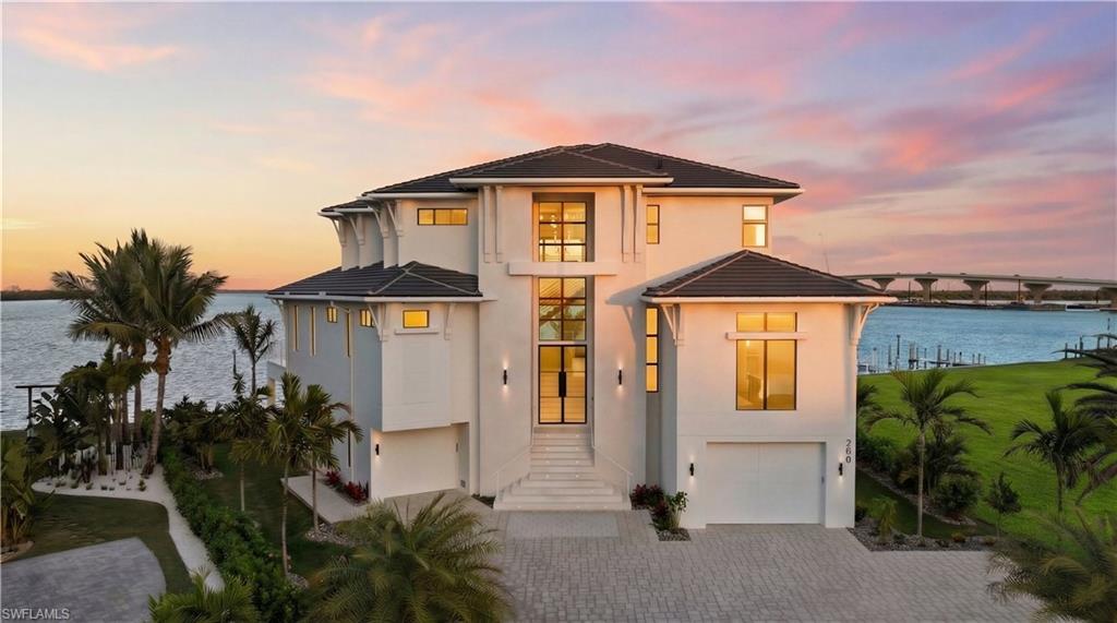 EXCEPTIONAL NEW CONSTRUCTION COMPLETED MARCH 2026 — COASTAL LUXURY, PERFECTED!

Introducing a newly constructed bayfront residence where uncompromising craftsmanship, architectural elegance, and engineered strength converge in one of Fort Myers Beach’s most desirable locations. A HOME LIKE NO OTHER, this refined coastal home with 12,200 square feet under roof, is designed for durability, beauty, and elevated living, capturing expansive water views across Estero Bay and toward the iconic new FMB bridge—offering dramatic scenery by day and illuminated vistas by night.

From inception, solid masonry construction supported by over 130 concrete pilings establishes a foundation of coastal resilience. Concrete floor systems and an Eagle Capistrano cement tile roof enhance long-term performance and peace of mind. The home’s orientation maximizes sweeping bay views while filling the interior with natural light. Handcrafted finishes create a sophisticated yet welcoming atmosphere. Statement ceilings showcase curated woods including rift-sawn white oak, sycamore, rift-sawn maple, and curly maple, complemented by custom-milled doors, oversized trim, and crown molding. Large-format shell stone flooring flows throughout main living areas and stairways, while 10-inch-wide engineered white oak flooring adds warmth to bedrooms and the flex lounge. The great room features a custom entertainment wall with a three-sided fireplace and an 85-inch Frame TV. The designer kitchen is appointed with Sub-Zero, Wolf, and Bosch appliances, custom cabinetry, concealed pantry storage, a substantial center island, and Taj Mahal quartzite and Matarazzo dolomite surfaces. Spa-inspired baths include floating cabinetry with integrated electrical outlets, frameless glass showers, and curated tile selections. A private elevator provides seamless access across all levels, while a fully integrated smart home system enhances connectivity and security. Outdoor living offers a resort-style experience overlooking the bay. The expansive outdoor kitchen and entertaining area features custom concrete, shell stone, and stainless cabinetry, a 12-foot powder-coated radius seating bar with Spanish stone top, built-in Infratech radiant heaters, and a 360 Breeze misting fan system. The sculptural pool and spa include a negative-edge spillover, glass tile finishes, sun shelf with bubblers, underwater seating, LED lighting, and a raised spa with dual spillways. A private dock with dual boat lifts and new seawall provide direct bay access. A heated outdoor cabana, fire pit, and pizza oven complete this exceptional waterfront setting. Marine-grade stainless steel and powder-coated railings, power roll-down hurricane and insect screens, and professionally finished exterior elements complete the design. Every detail is thoughtfully selected to deliver luxury without compromise—merging architectural integrity, coastal strength, and an extraordinary bayfront setting.
