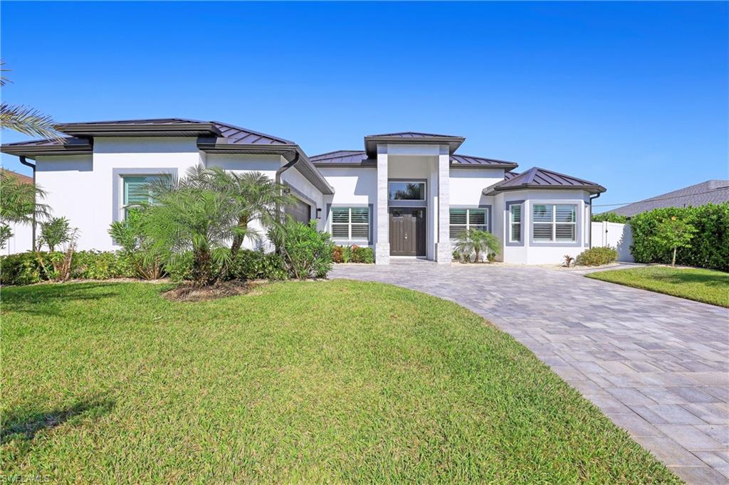 Amazing Newer Home located in one of the Best Locations in Cape Coral.  Close to Cape Harbour and more.  Hurricane Impact Windows, and 8' Tall Impact Sliders,  Assessments are Paid in Full,  Standing seam metal Roof, paver driveway to the side loader garage and on both sides of the house and on to back lanai and surrounding pool and tanning area.  8' Tall Wood double door entryway with a transom window over.  The entire home has white 24" Tile Flooring and 8' Tall interior doors, Crown Molding, 5" Baseboard molding.  Almost all windows have custom wood white plantation shutters. On the sliders there are custom accordion fabric privacy shades. There is a custom wall of tile and a built in designer wall fireplace in the Great Room.  The kitchen offers a huge Quartz countertop Island with Quartz waterfall and European white cabinetry.  3 Full Baths and a shower head by the pool.   New outside kitchen island with granite countertops and stainless drawers for organization.  There is also a built in Barbeque, sink, Refrigerator and prep area.  Oversized pool and large Tanning area.   Must be seen to be appreciated
