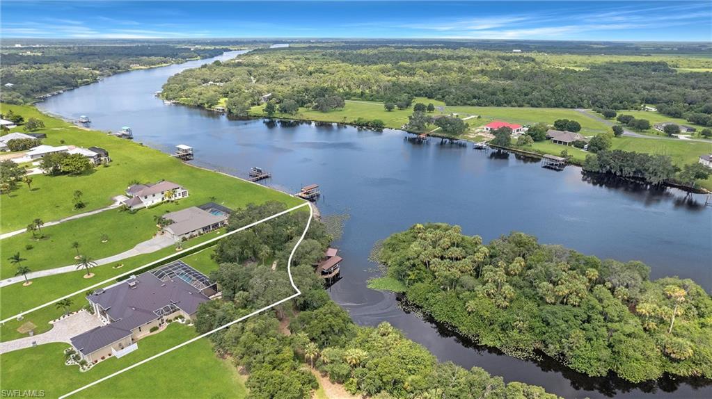 Distinguish yourself with this Traditional Modern beauty—4200+ SF with amenities to infinity! Well-located close to Fort Myers/Naples for easy access to work or shopping but located in the quiet country-side of Fort Denaud. This location on the intracoastal Caloosahatchee River has both new river frontage for boat traffic views and old river for native tropical views with protected boat harborage. This spectacular residence is 3 bedrooms/4.5 baths with an attached game/music room which could also be an in-law or guest apartment. Home exterior includes a pool/spa in a panoramic view pool cage, outside kitchen with bar, fire pit with circular seating, dock with roofed new river gazebo and covered old river boat lift. Home interior features formal entry, living room, family room, dining room, chef’s kitchen with casual dining area, butler’s pantry, office, laundry room, master bedroom suite, two ensuite guest bedrooms, and oversized garage with separate air conditioned storage room. Everyone will love cooking in the show-stopping kitchen with stacked cabinets, the best of appliances and two islands. The master suite has a walk-in closet and Waldorf Astoria wardrobe system.