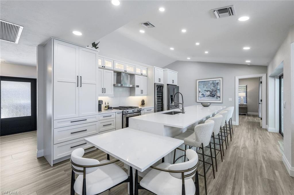 Experience modern coastal living at its finest! This extensively renovated and redesigned 3-bedroom, 2.5-bath pool home boasts meticulous upgrades and thoughtful details. Enjoy peace of mind with all new permitted electrical, plumbing, and impact-resistant windows and doors. Take pleasure in the convenience of a New seawall and dock complete with water and a 16,000 lb boat lift – perfect for waterfront adventures! Inside, discover a beautifully reimagined space with LED lighting, water filtration, and even an acoustic wall for enhanced living. The primary suite is a dream, offering custom closets, a luxurious walk-in shower, private water closet, and dual vanity with automated lighting. Entertaining is a breeze in the gourmet kitchen featuring quartz counters, KitchenAid appliances (including a gas stove), a wine cooler, a 5-seat bar, touchless faucet, and a wet bar with lanai access. Additional highlights include new bathrooms with quartz counters, a solar-heated pool, a 2017 roof, AC garage with new hurricane rated door, mini-split and storage, fruit trees, extra insulation, new PEX plumbing, new sewer lines,  handicap accessibility, and desirable southwest exposure. Even the yard boasts meticulous touches like a French drain system and an outdoor shower. Plus, enjoy limitless hot water with the tankless on-demand system.