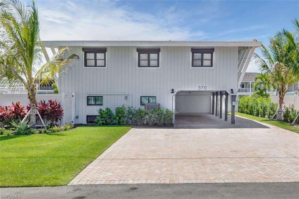 Elevated, waterfront, pool home with direct Gulf access - bursting with coastal charm. The main level features two naturally bright bedrooms and two completely remodeled bathrooms, beautifully furnished in a modern coastal style and overlooking the sparkling pool next to the deepwater canal. Two boat docks, a 16,000 lb lift with fishing area and a 7,000 lb lift for jet skis, smaller vessels and water toys. Downstairs, a fully renovated one bedroom apartment offers a full kitchen, an open living area with pool views, elegant bathroom and a separate vanity with multiple closets — perfect for guests, rental income or multigenerational living. Entertaining and privacy are effortless with multiple outdoor living spaces including a breezy screened upstairs lanai, a lively downstairs pool deck area with bar, and a rooftop observation point with panoramic views of the Back Bay and island hotspots. Comfort and convenience mingle together with a large heated pool with newer equipment, expansive deck, an outdoor shower to rinse off after a day of fun in the sun, a newer roof (2023), impact glass sliders and electric shutters for the single hung windows and sliders for added security and peace of mind. Lush, mature tropical landscaping throughout the grounds and abundant storage make it simple to close up and escape for extended getaways. Prime mid island location with easy beach access, golf cart shopping at Publix and dining at local favorites like Junkanoo or Fresh Catch. Watch dolphins play in your backyard, cruise to neighboring islands and chase unbeatable sunsets over the Gulf on powder white sand. Endless possibilities to create your best Florida lifestyle!