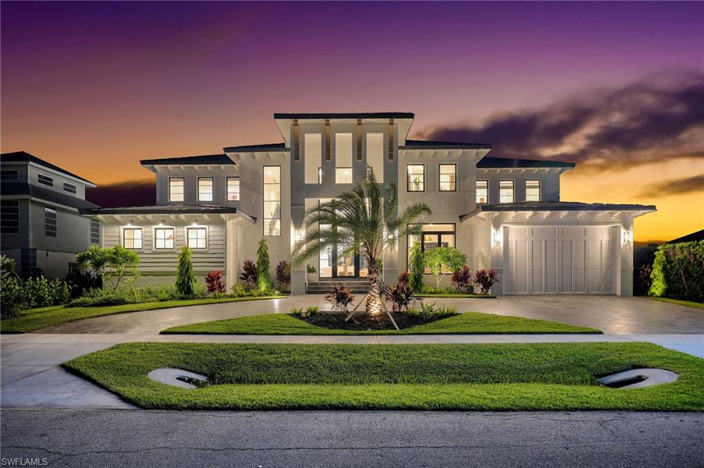 Welcome to a newly completed Marco Island estate where European elegance meets Gulf Coast serenity. This residence sets a benchmark in refined craftsmanship, with curated finishes designed to elevate both daily living and the waterfront lifestyle. The exterior makes a bold architectural statement, while a hurricane impact metal and glass pivot door opens to a soaring 24 ft foyer with wide plank European white oak floors throughout.

Just off the entry, a powder bath features German imported wallpaper over custom paneling. Arched white oak doors lead to a flexible office ideal for remote work, library, or wine room. An oak staircase with sleek black railings conceals a private media room and connects to an upstairs poured concrete slab engineered for soundproof, multigenerational living. A white oak wrapped elevator provides seamless access between floors.

The formal living room is anchored by an electric shellstone fireplace beneath custom white oak beams. Built-ins, curated lighting, and hurricane impact pocket doors open the space to the water. The dining room offers designer lighting for elevated entertaining. The chef’s kitchen showcases honed Italian Arabescato marble with double ogee edges, custom white oak cabinetry, Venetian plaster stove wall, aged unlacquered brass hardware from London, a 48” ILVE Nostalgie dual fuel range, and a paneled Miele appliance suite. A hidden English inspired scullery adds walnut butcher block counters, prep sink, coffee bar, open shelving, and storage with Brizo and Delta fixtures.

The family room centers on a custom wet bar with wine fridge and ice maker. Whole home smart integration extends to audio and climate. The finished two car garage features epoxy floors and an 18 ft insulated door.

The main level primary suite offers 12 ft ceilings, custom paneling, imported Roman shades, dual California Closets with integrated lighting, and a spa inspired bath with Dolomite marble, limestone floors, Roca mosaic feature wall, polished brass fixtures, and a wallpapered water closet.
Upstairs are four ensuite bedrooms with custom paneling and imported wallcoverings. Baths feature curated marble, limestone, and porcelain finishes with brass fixtures. A loft living area includes a wet bar and opens to a travertine clad waterfront balcony. The laundry room features checkerboard limestone floors, marble counters, ThinQ appliances, deep sink, and custom cabinetry.

Outdoor living is resort level with a saltwater pool, infinity edge spa, shellstone decking, full summer kitchen, beer tap, cabana bath, and vintage cast iron sink. The 70 ft composite dock offers deepwater Gulf access with no bridges. Additional highlights include hurricane impact windows and doors, custom millwork, designer lighting, and hand selected European fixtures. This Marco Island estate delivers timeless coastal luxury with modern performance.