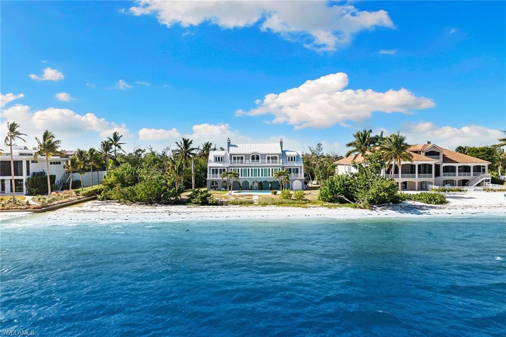 Experience the pinnacle of coastal living with this extraordinary 5,542-square-foot beachfront residence on Sanibel Island. Positioned on a private .86-acre lot adjoining protected conservation land and boasting 150 feet of waterfrontage. Designed for elegance and comfort, this four-bedroom estate captures sweeping bay views from nearly every room, the home features gracious living and dining areas with a fireplace and walls of glass that open to breathtaking panoramas. The expansive layout includes an inviting spacious kitchen with wide water views, a luxurious and spacious primary suite, a private office, and a serene sitting room to enjoy bay views, all accentuated by timeless hardwood flooring and impact-rated windows and doors. The top floor houses guest suites and a second primary suite. Gi outside to an inviting heated beachfront pool overlooking the wide bay, an ideal setting for tranquil relaxation or refined entertaining. With unmatched privacy, stunning natural surroundings and potential to create a private world-class single-family retreat, this property offers an exceptional opportunity to own one of Sanibel Island’s desired waterfront addresses. The home received damage to the lower non-living area during Hurricane Ian, the pool and garage have been restored, but storage areas, landscape and irrigation system requires repairs and updates. The home is in the sought-after area of Bird Lane within a few minutes of the Sanibel causeway and bridge for easy access on and off the island and offers incredible potential for updating and personal touches. The home is being offered in as-is condition.