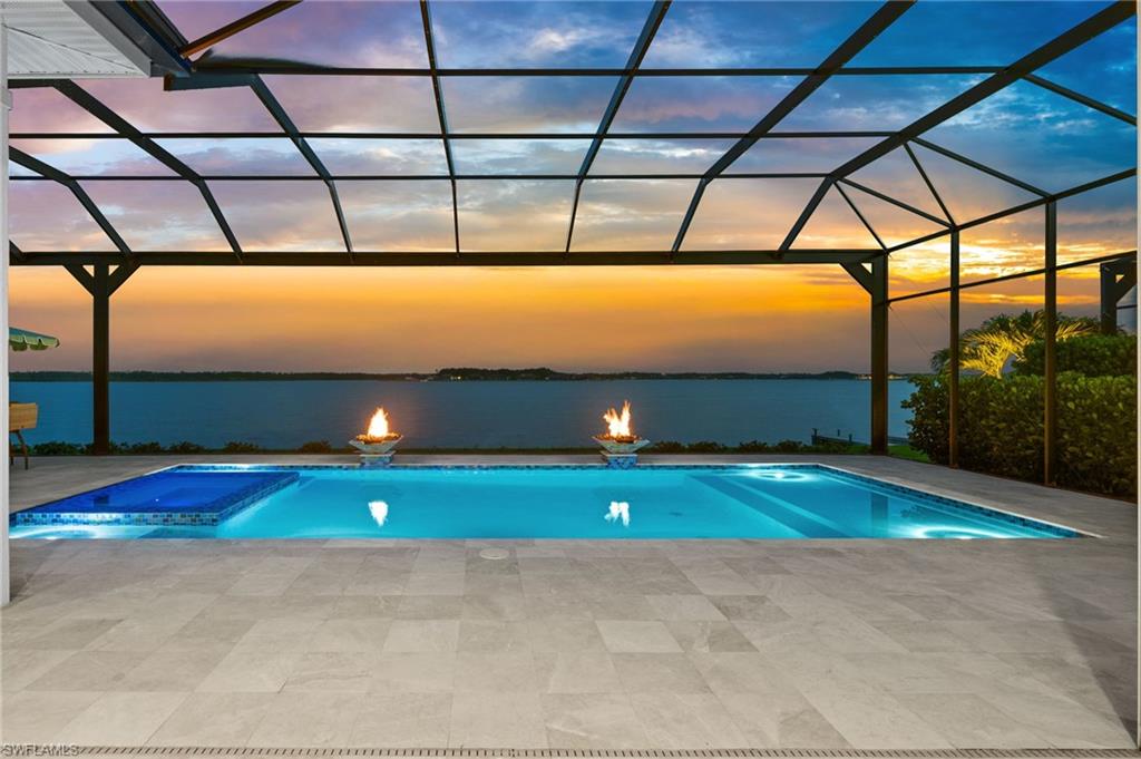This stunning, custom home built by Stock Development, offers waterfront living at its finest, showcasing breathtaking Lake views in the prestigious WildBlue community! Offered furnished, every detail of this meticulously styled 4 Beds, 4.5 Baths, Den and an oversized 3 car garage home have been carefully curated to provide comfort, convenience, and luxury living. Upon arrival, an extensive setback from the street establishes an impressive curb appeal, complemented by a circular driveway, custom landscape and lighting, and custom glass and metal front doors which create a grand entrance. The great room serves as the heart of the home with a stunning feature wall showcasing a beautiful fireplace and recessed 75-inch TV, enhanced by a Sonos sound system that extends to the lanai, primary suite, and guest bedroom. The gourmet kitchen is designed for both everyday living and entertaining, featuring quartz countertops, custom backsplash, extended-height illuminated cabinetry, under and above-cabinet lighting, a Wolf gas cooktop with griddle, warming drawer, wine fridge, oversized high-performance exhaust system, and abundant storage. Inside, custom details elevate every space. Enjoy premium wood flooring throughout, updated lighting fixtures, coffered and tray ceilings with custom soffit lighting, and built-in closets in the primary and guest bedrooms. The study showcases extensive built-in cabinetry, display shelving, plantation shutters and stylish barn doors. The luxurious primary suite features double glass doors that conveniently open to the lanai and a spa-like ensuite making it a great space to relax and unwind and dual walk-in closets. Each guest bedroom provides comfort and privacy complemented by their own full bathroom. Creating the ultimate Florida outdoor living experience, step outside for a true resort-style retreat. The expansive lanai features a picture frame pool cage, tray ceiling with decorative beams, custom outdoor kitchen with Hestan appliances, refrigerator, gas fireplace, electric storm shutters and a spectacular pool with dual fire-and-water bowls, swim deck, and an outdoor shower. The air-conditioned garage, extended an additional 4 feet, features insulated garage doors and ceiling, plantation shutters, NewAge storage unit, built-in storage closet, wall-mounted storage panels, and a whole-house Kinetico water filtration and softening system. Additional peace of mind comes with a 24KW Generac whole-home generator and comprehensive security system with outdoor cameras and video doorbell. Residents of WildBlue enjoy an unparalleled lifestyle and amenities which include an elegant lakefront clubhouse, indoor/outdoor dining, resort-style and lap pools, full-service spa, state-of-the-art fitness center, tennis and pickleball courts, bocce ball, boating, kayaking, and more. Perfectly positioned near several dining options, premier shopping, SW Florida International Airport, and the pristine beaches of Bonita Springs and Naples.